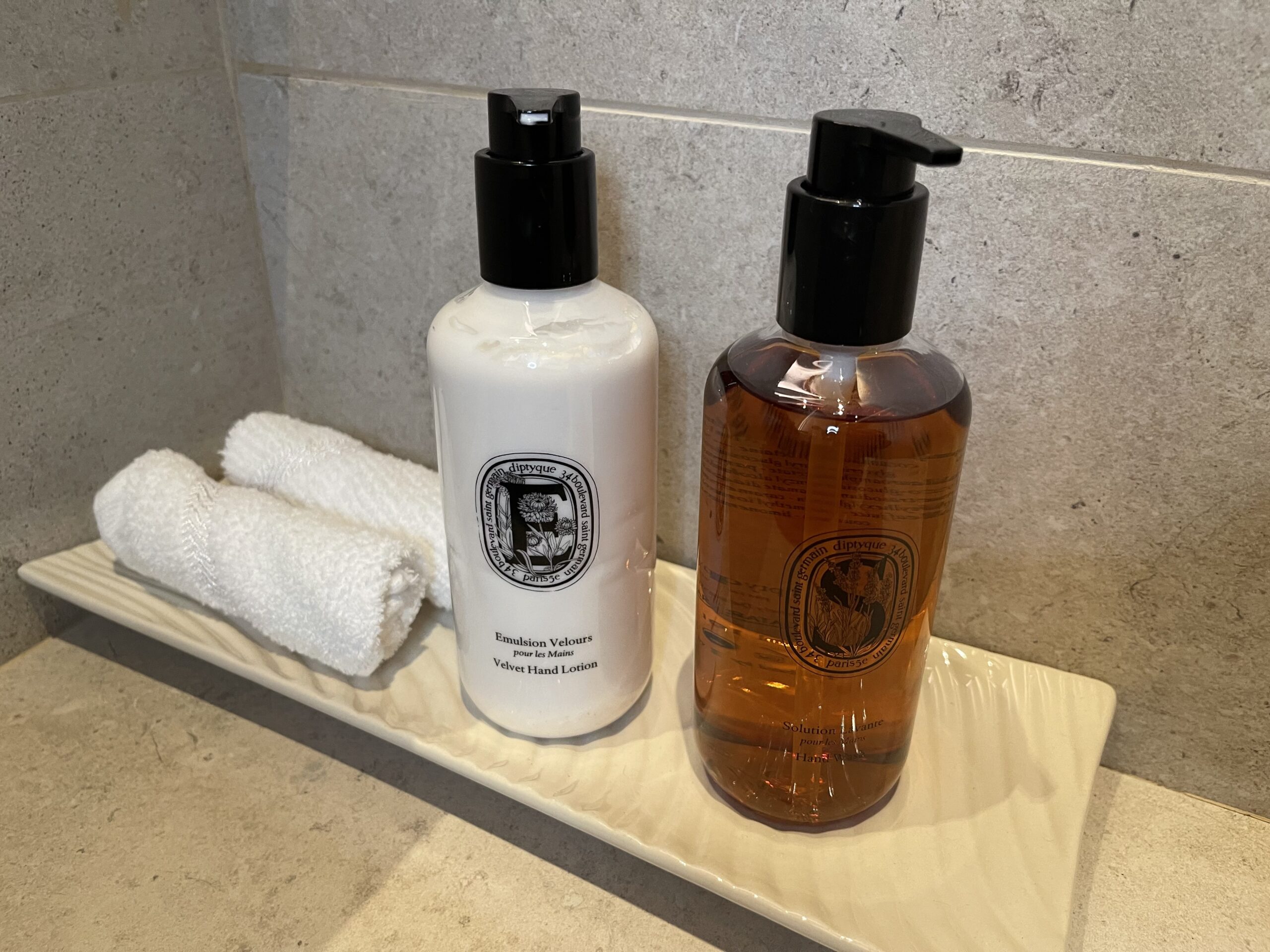 a white and brown bottles with black caps and a white towel on a white surface