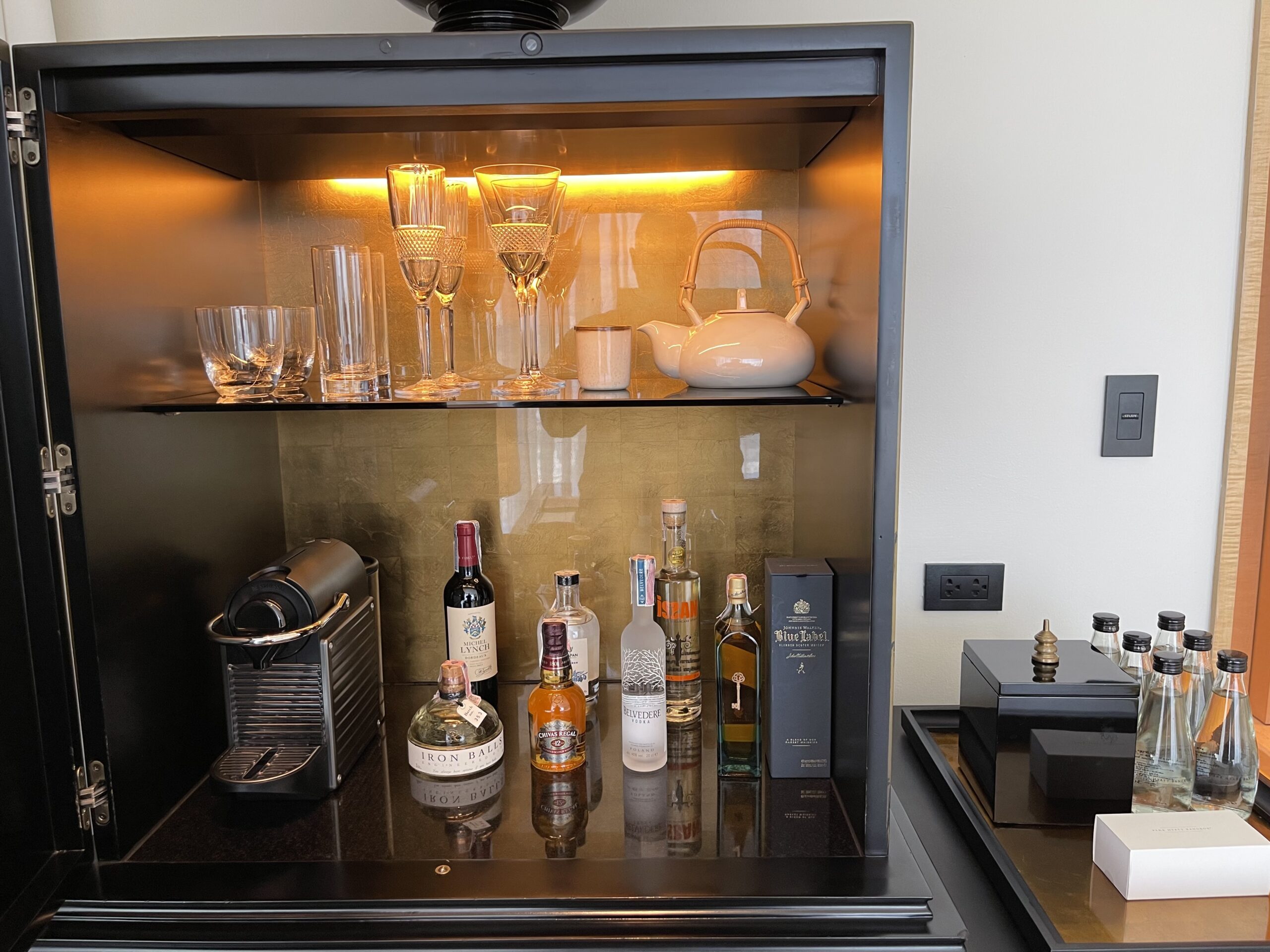 a glass cabinet with liquor bottles and glasses on top