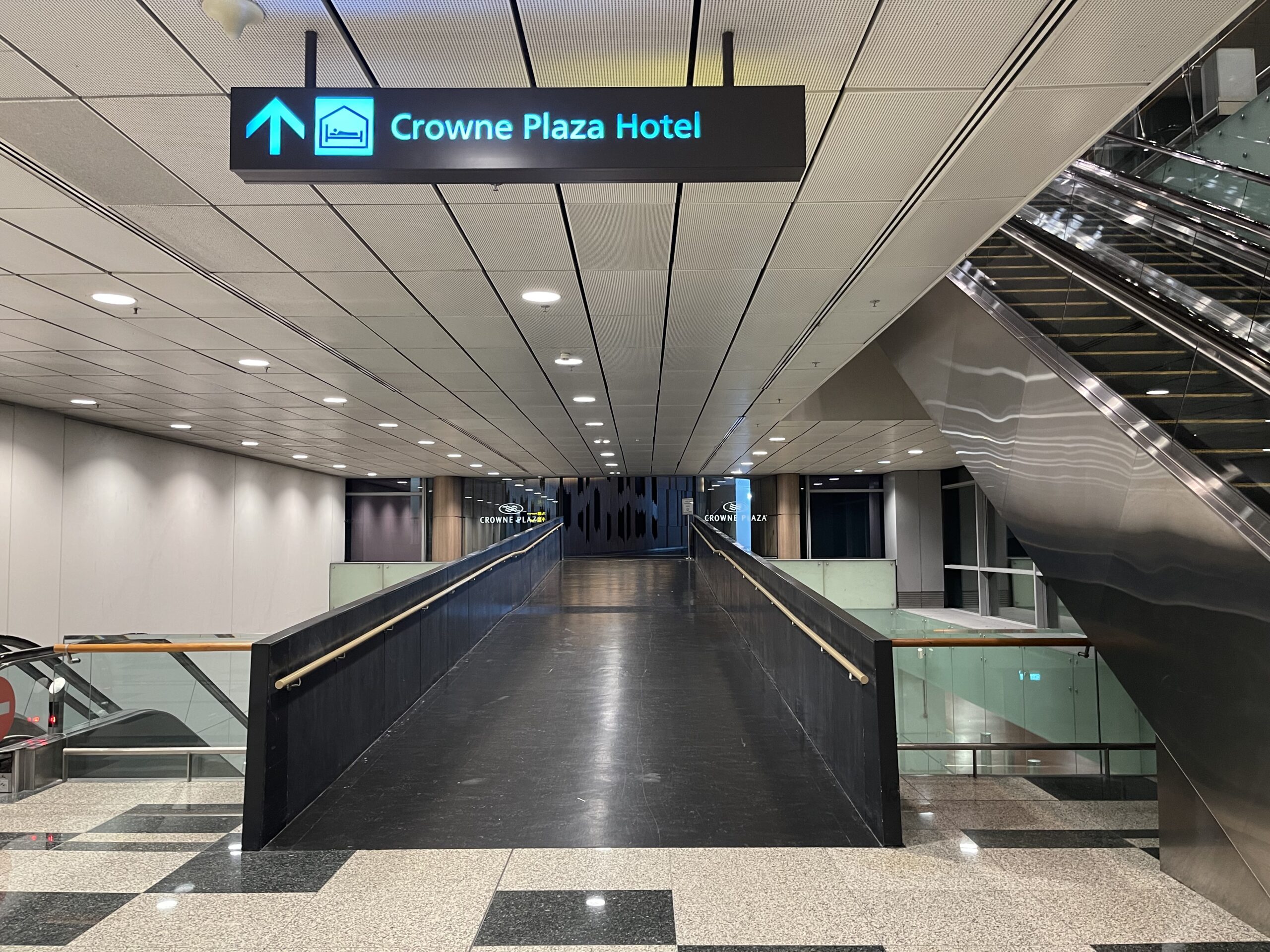 a walkway with an escalator and a sign