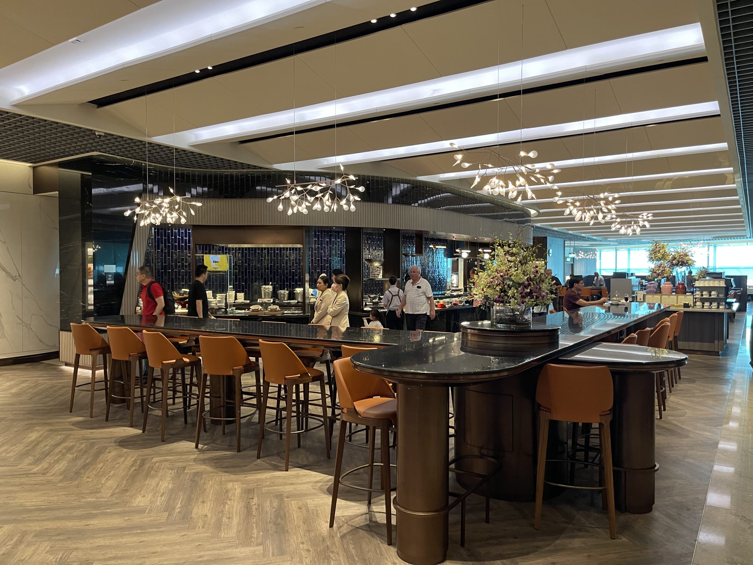 a large bar with chairs and people standing around