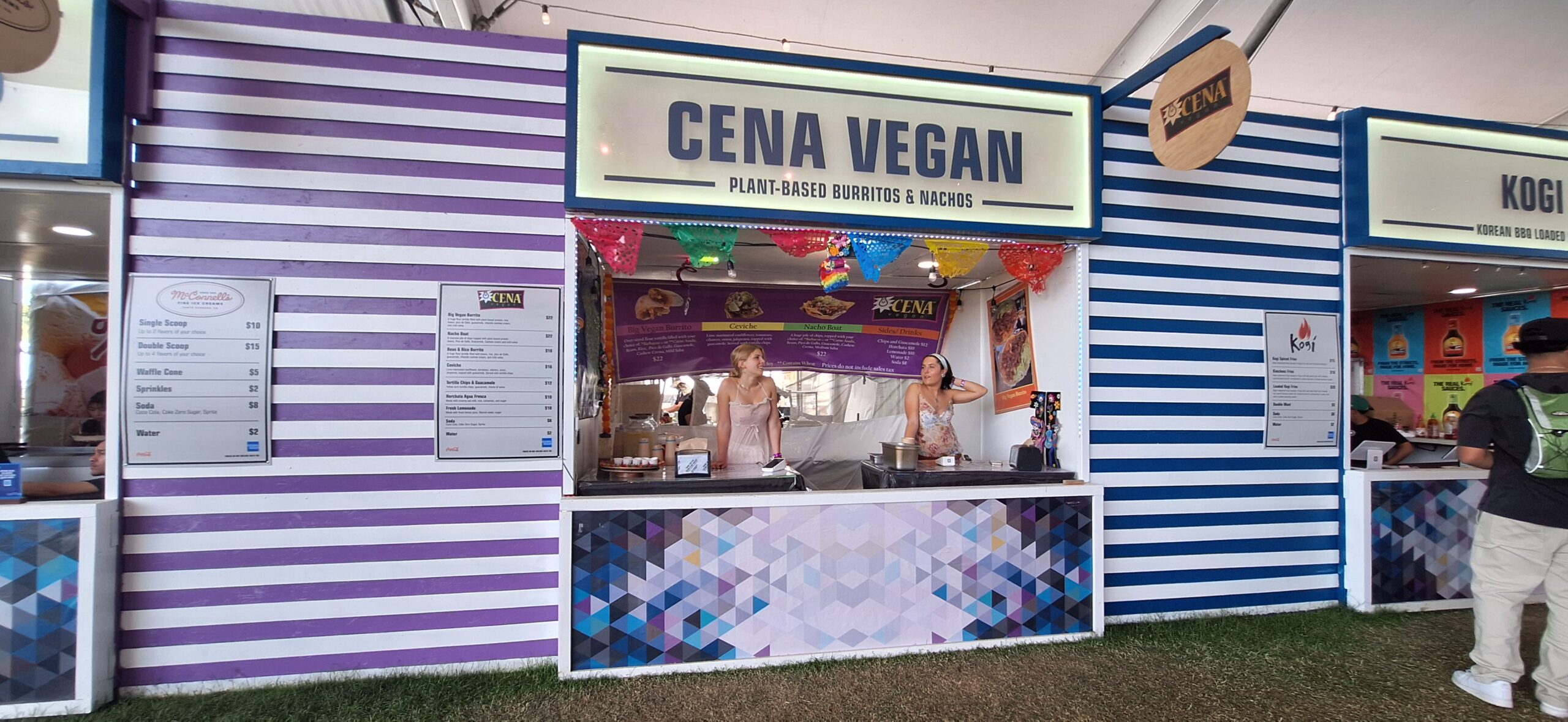 a two women standing behind a food stand