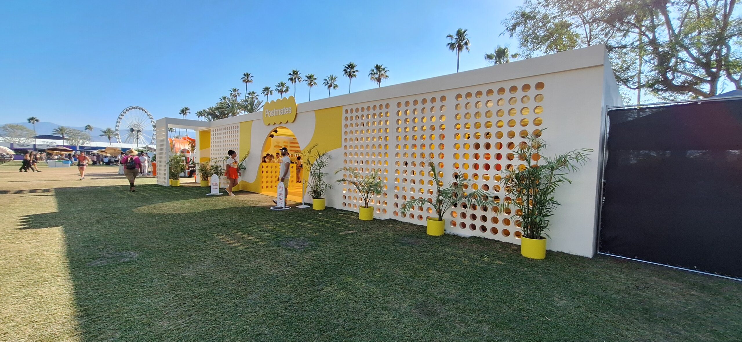 a white and yellow building with a white wall and yellow potted plants