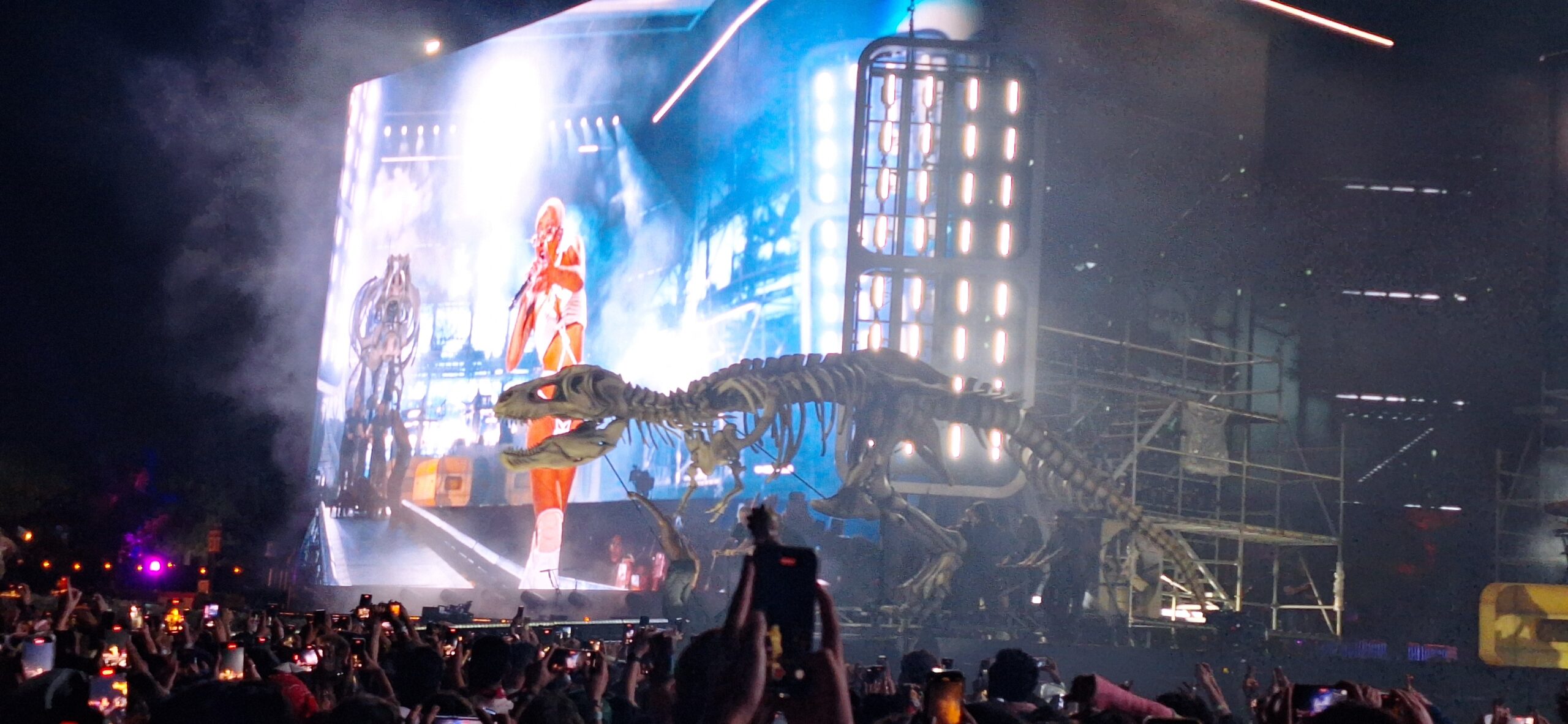 a group of people watching a dinosaur skeleton on a stage