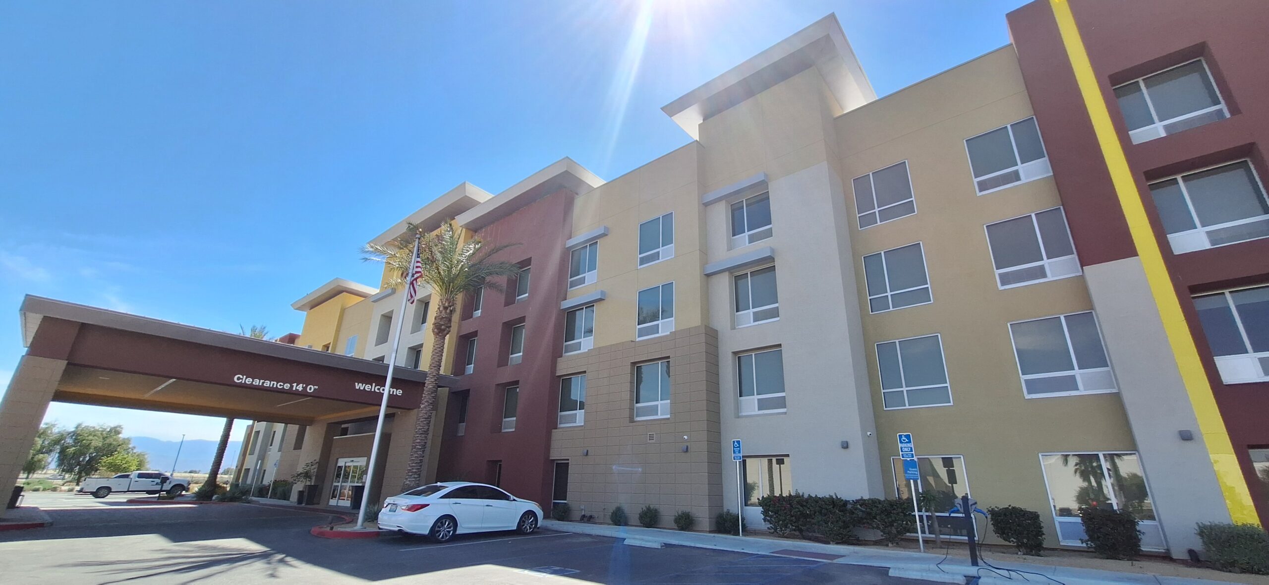 a building with a palm tree and a parking lot