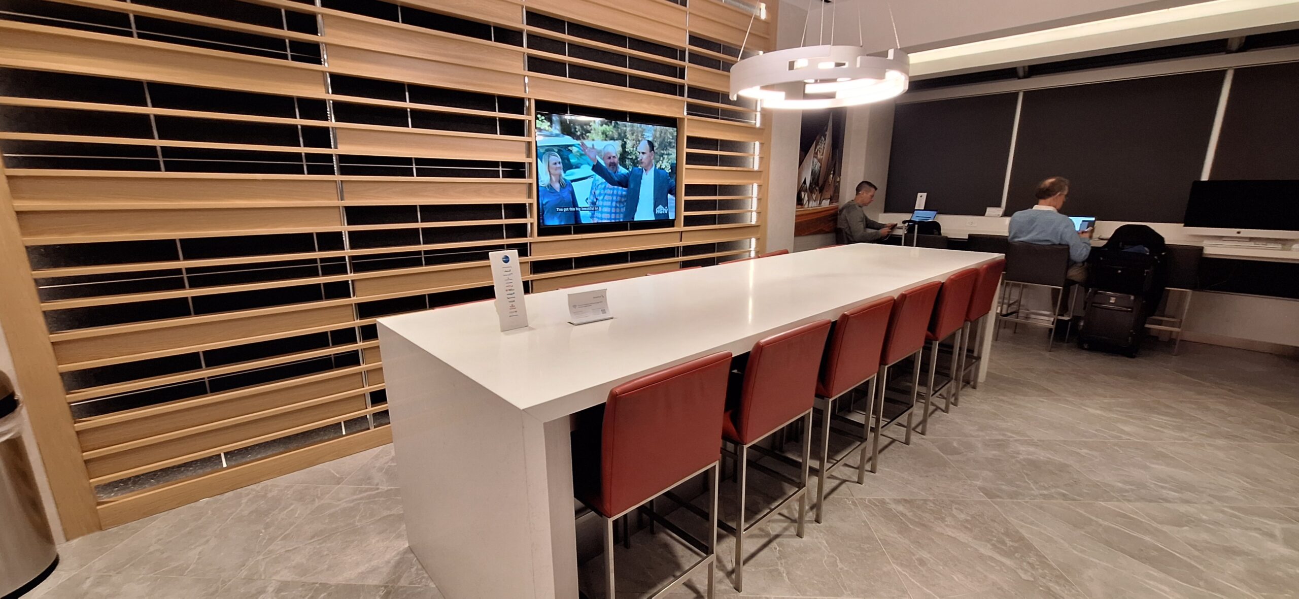 a long white table with red chairs and a television on the wall