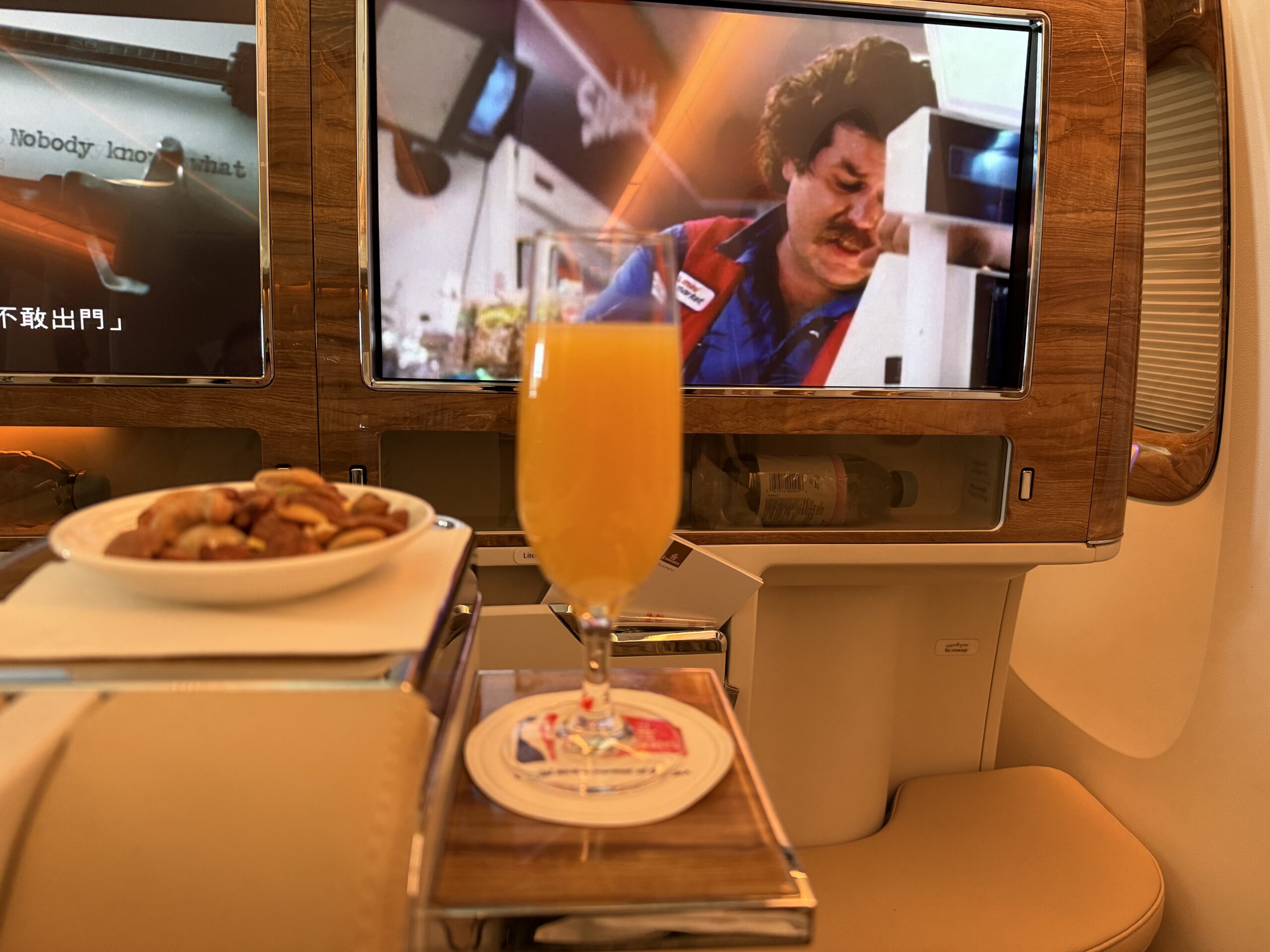 a glass of orange juice on a table with a plate of food on it