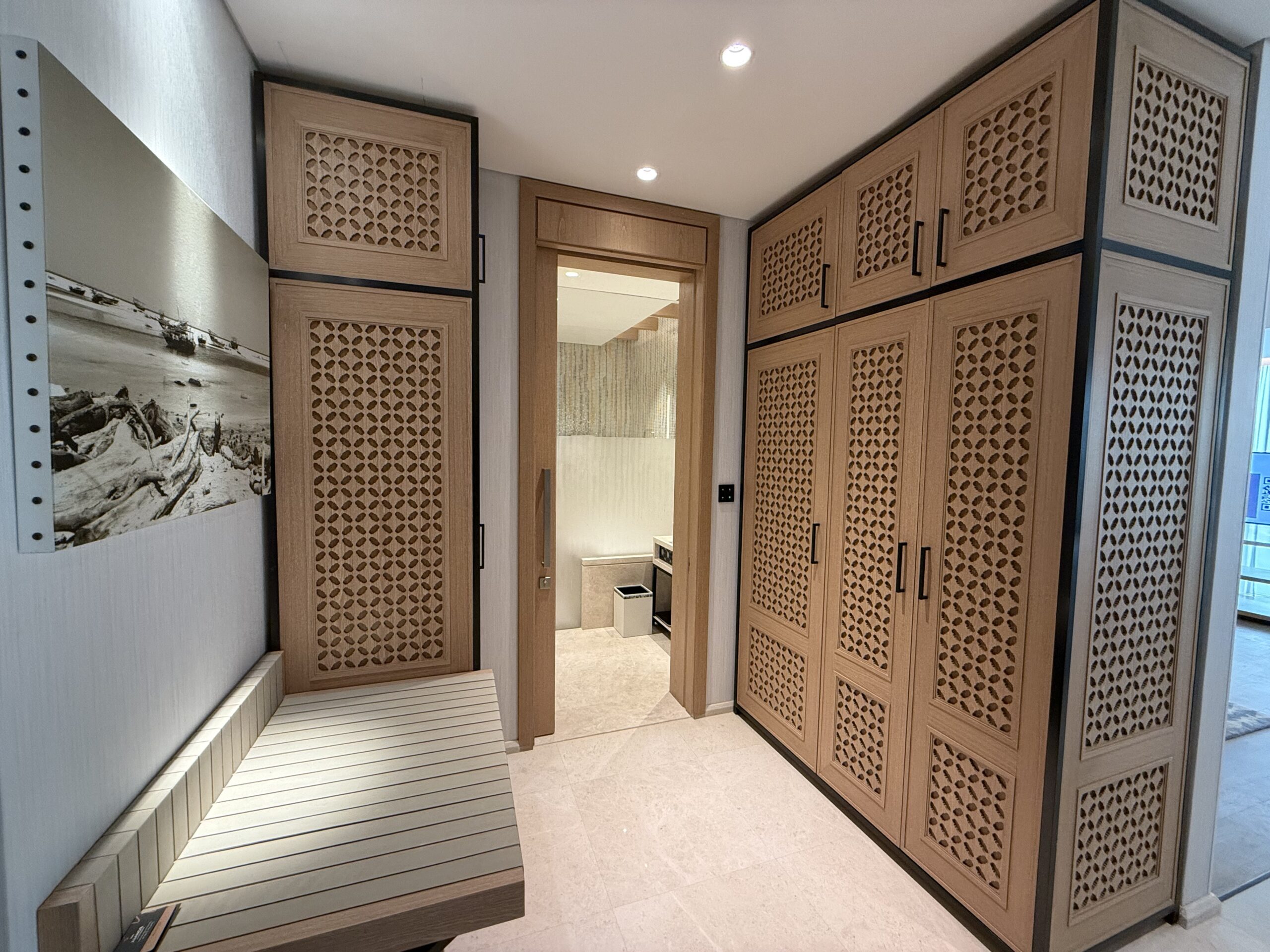 a hallway with wood cabinets and a bench