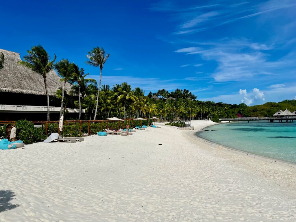 a beach with palm trees and a building French Polynesia