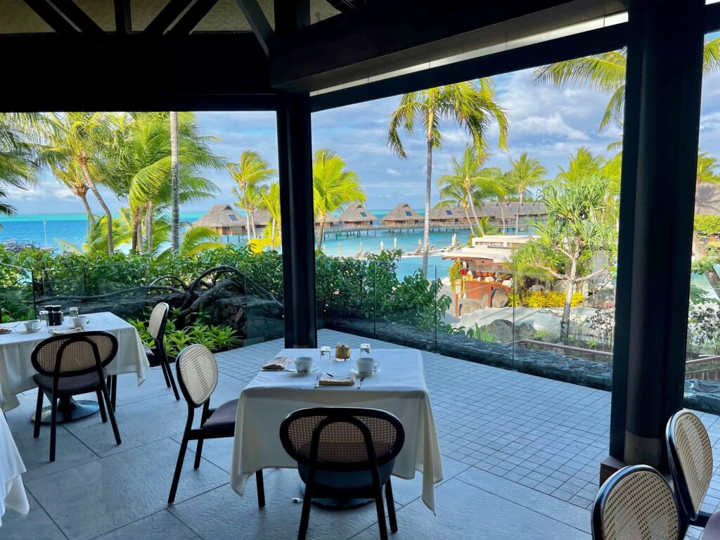 a table and chairs in a room with a view of the ocean and a beach