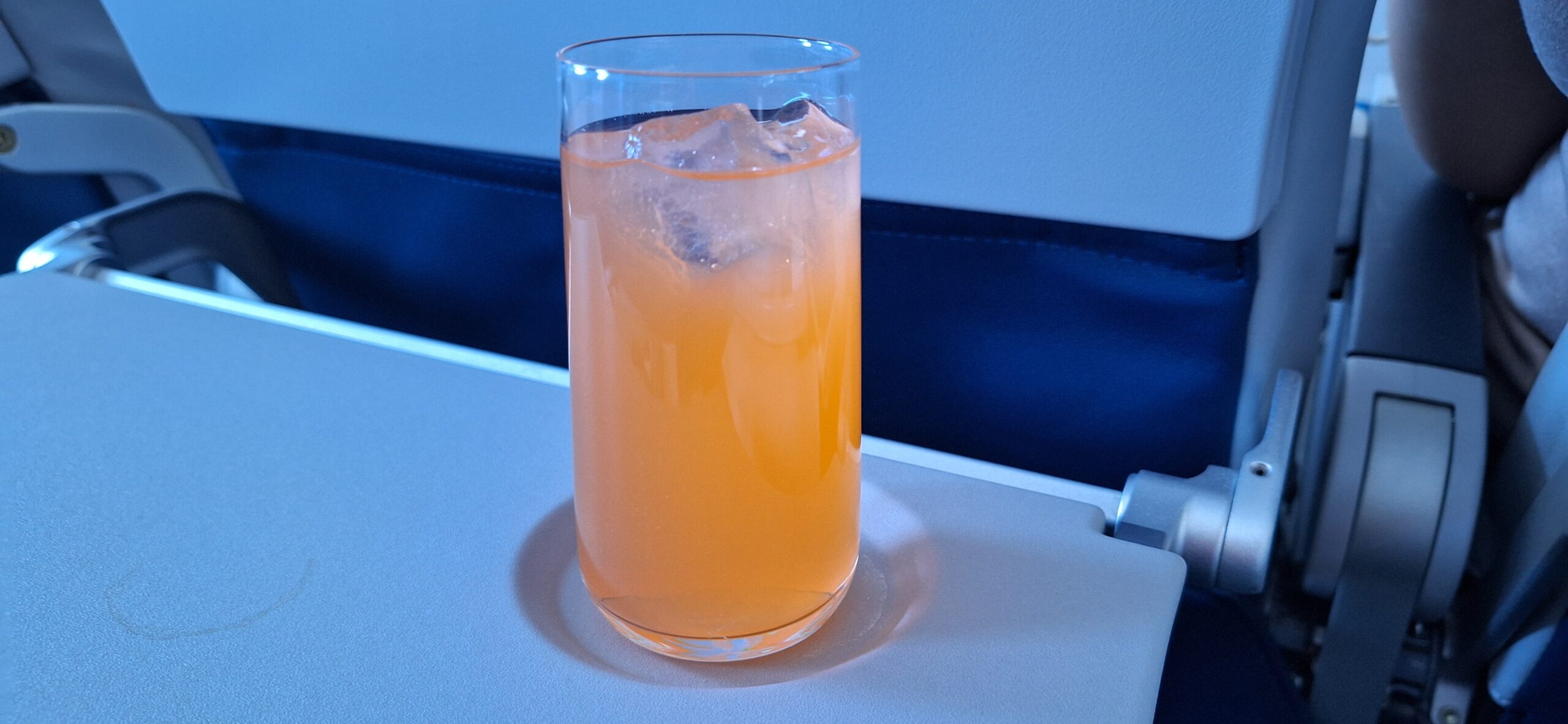 a glass of orange liquid with ice on a table