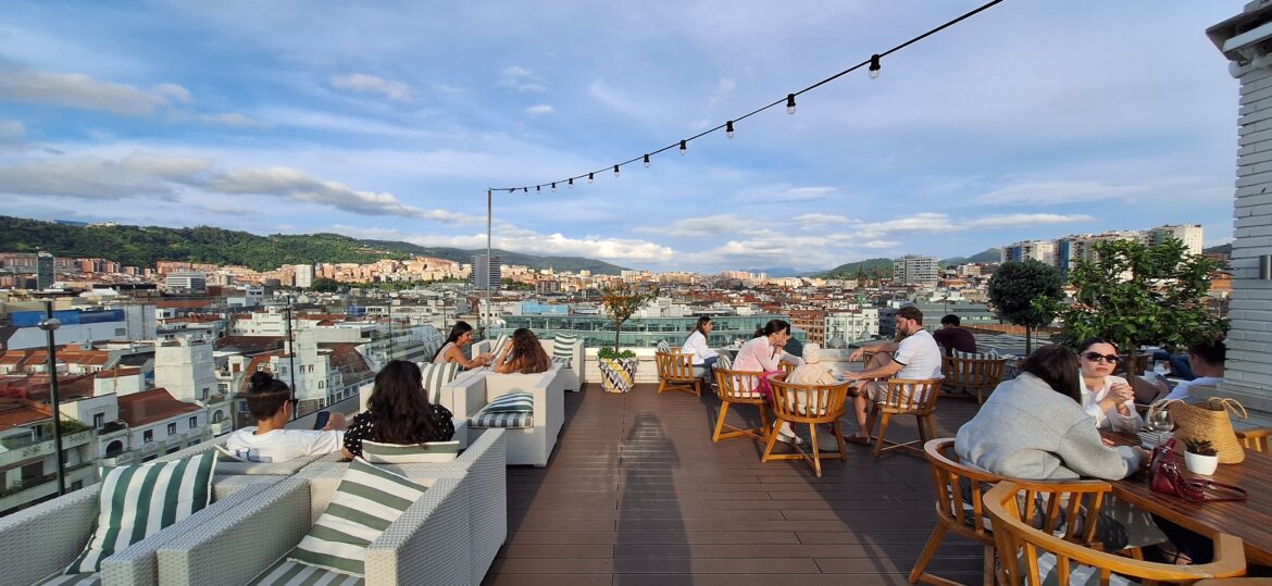 a group of people sitting on a deck with a city in the background