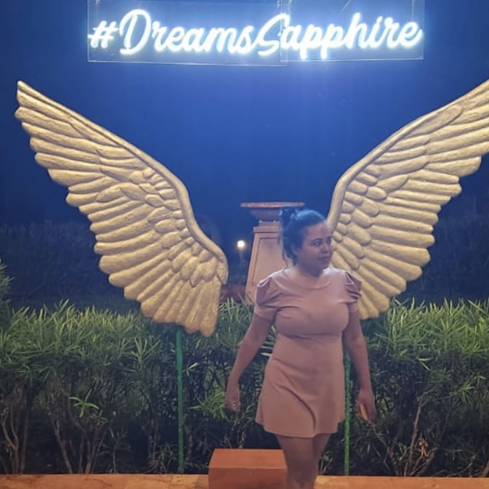 a woman standing in front of a sign with wings