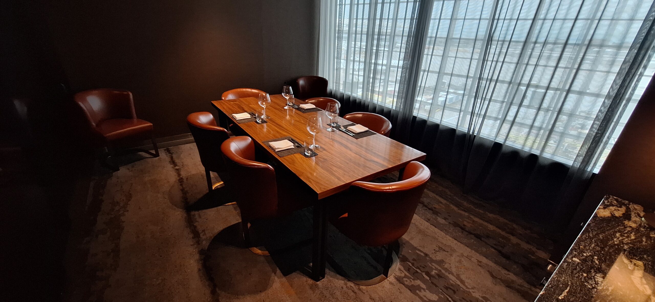 a table with wine glasses and chairs in a room with a window