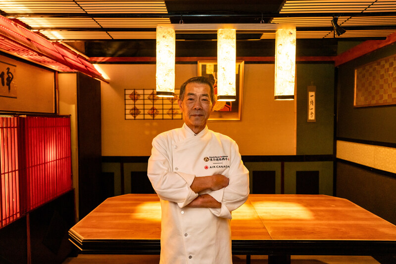 a man in a chef's uniform standing in a room with lights