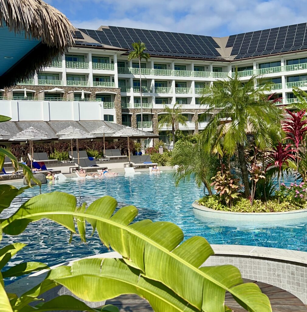 a pool with palm trees and a building with a blue sky
