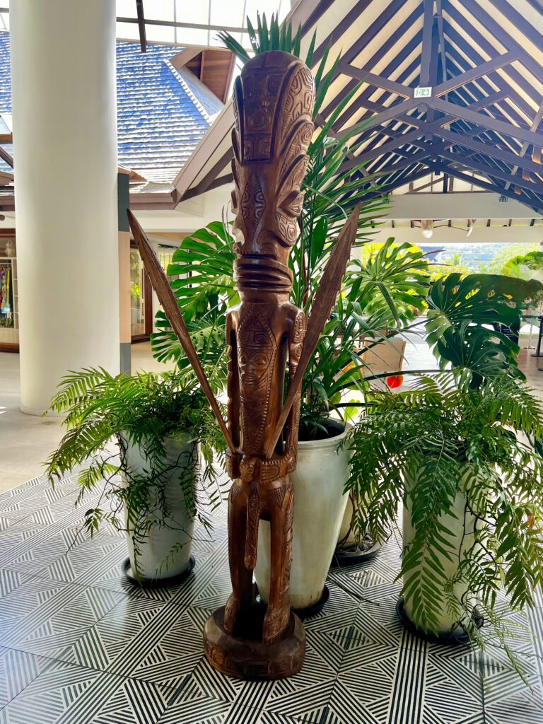 a statue of a man with a sword and a sword in a room with plants