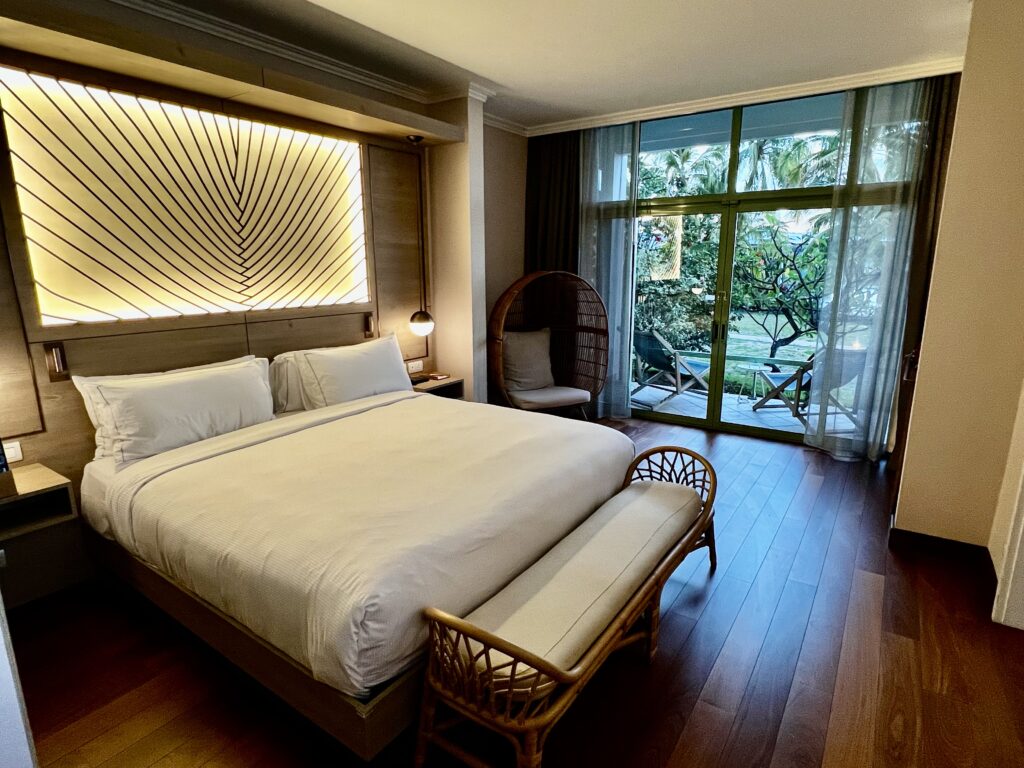 a bed with a wicker chair and a wicker chair in a room