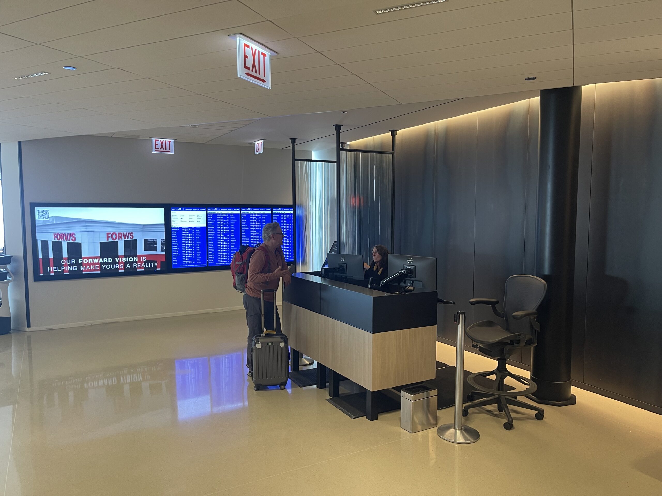 United Club Chicago ORD a man and woman standing at a desk in a lobby