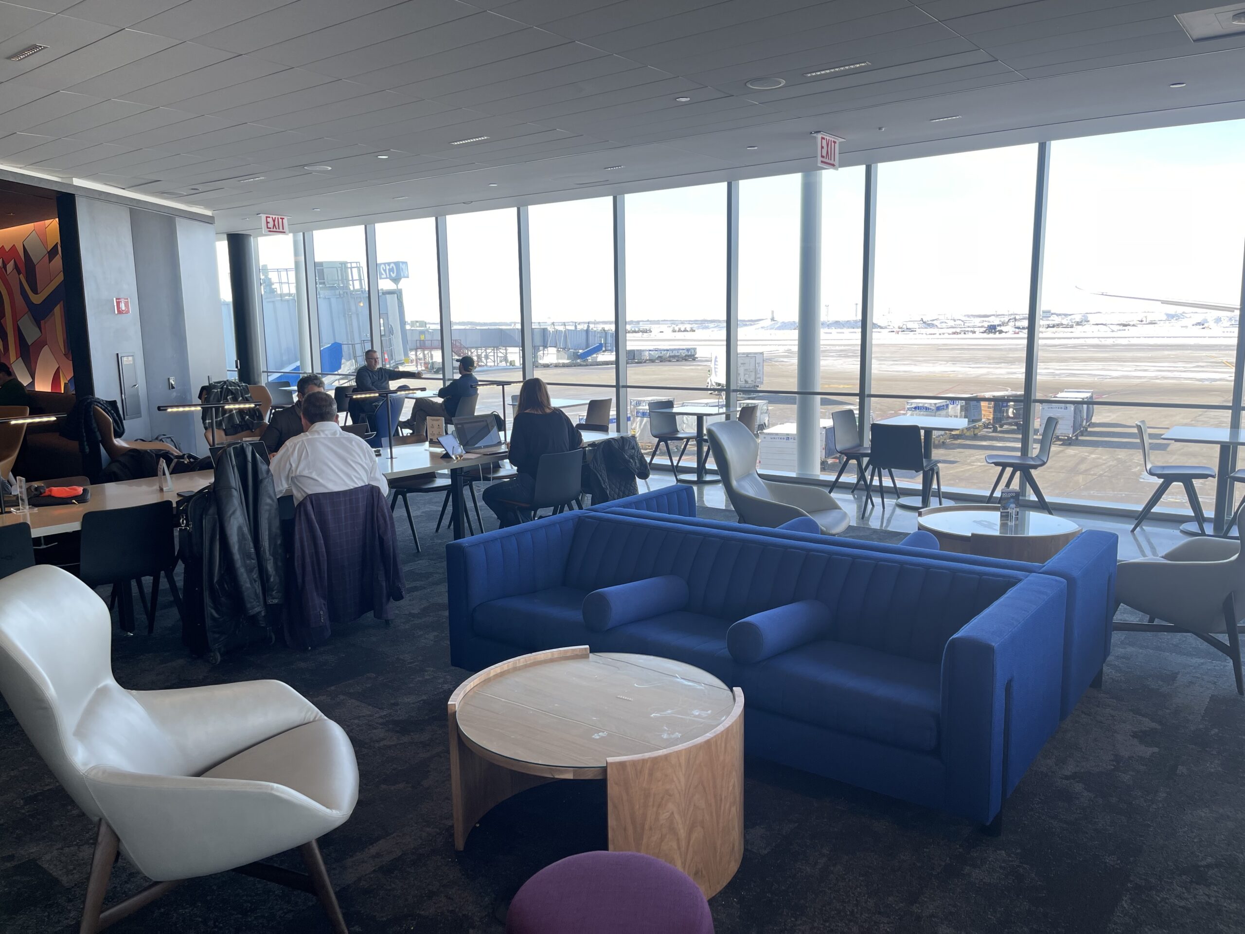 United Club Chicago ORD a room with a large window and people sitting at tables