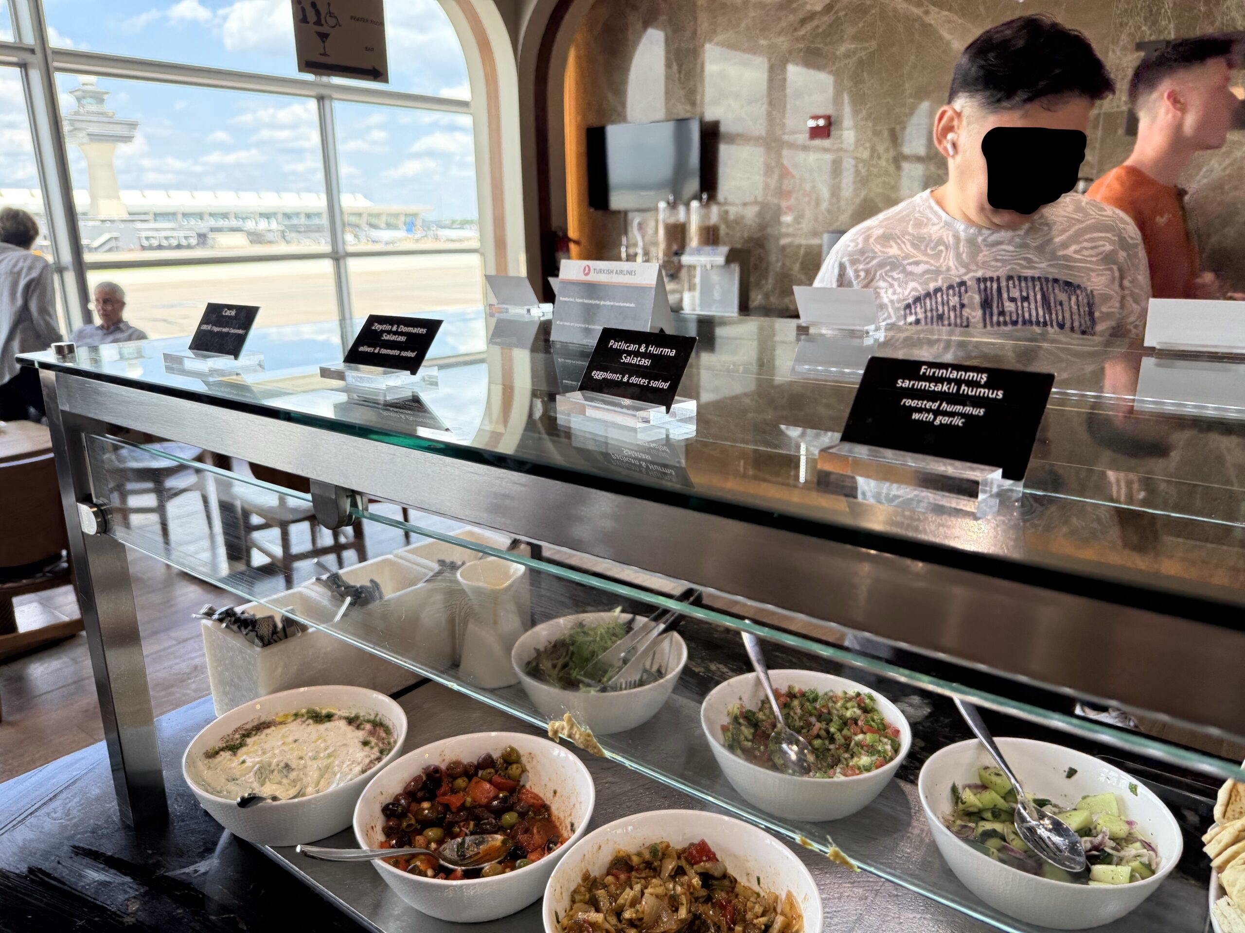 Turkish Airlines Lounge Washington a man behind a counter with bowls of food