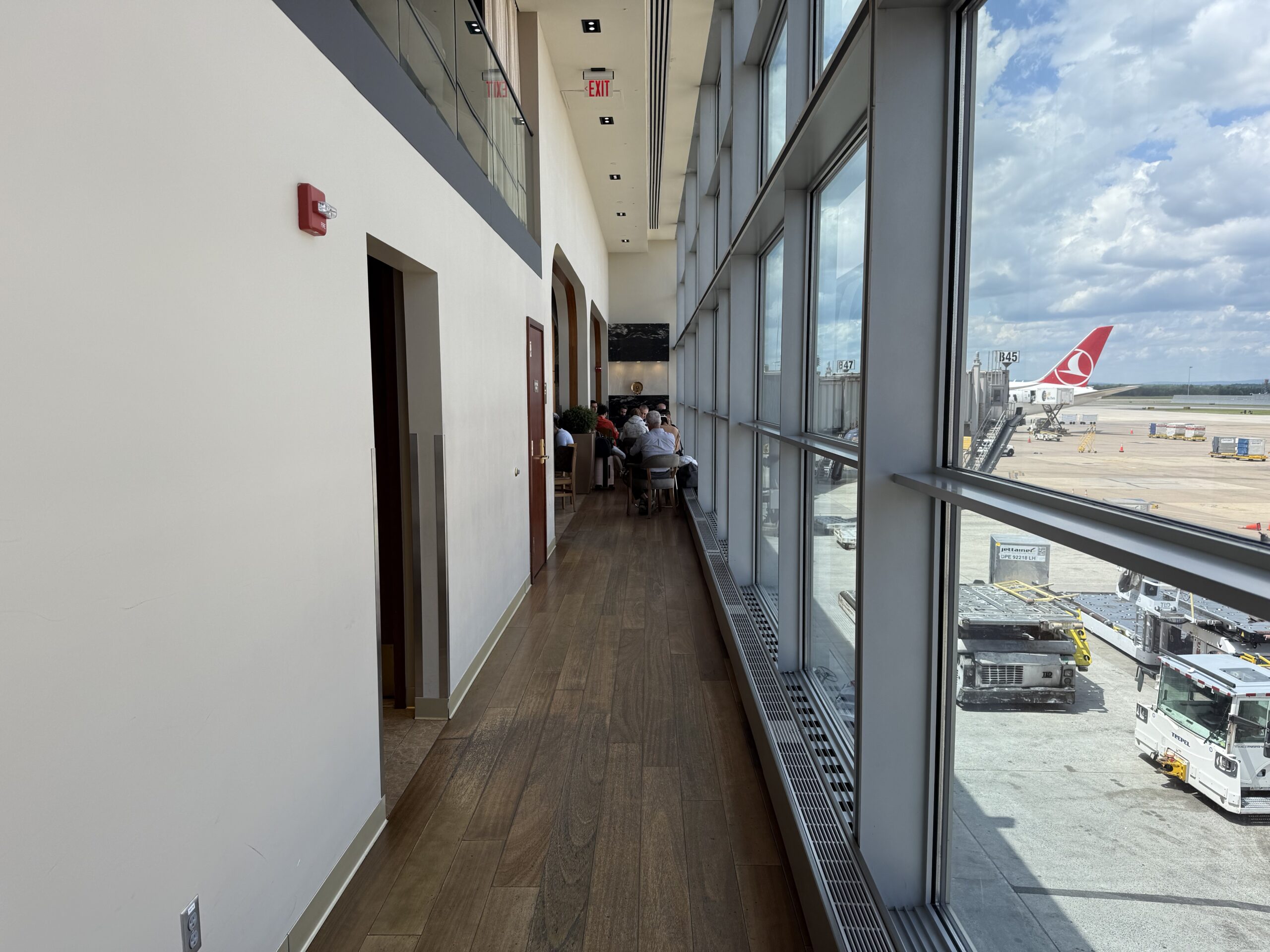 Turkish Airlines Lounge Washington a long hallway with windows and people sitting at tables