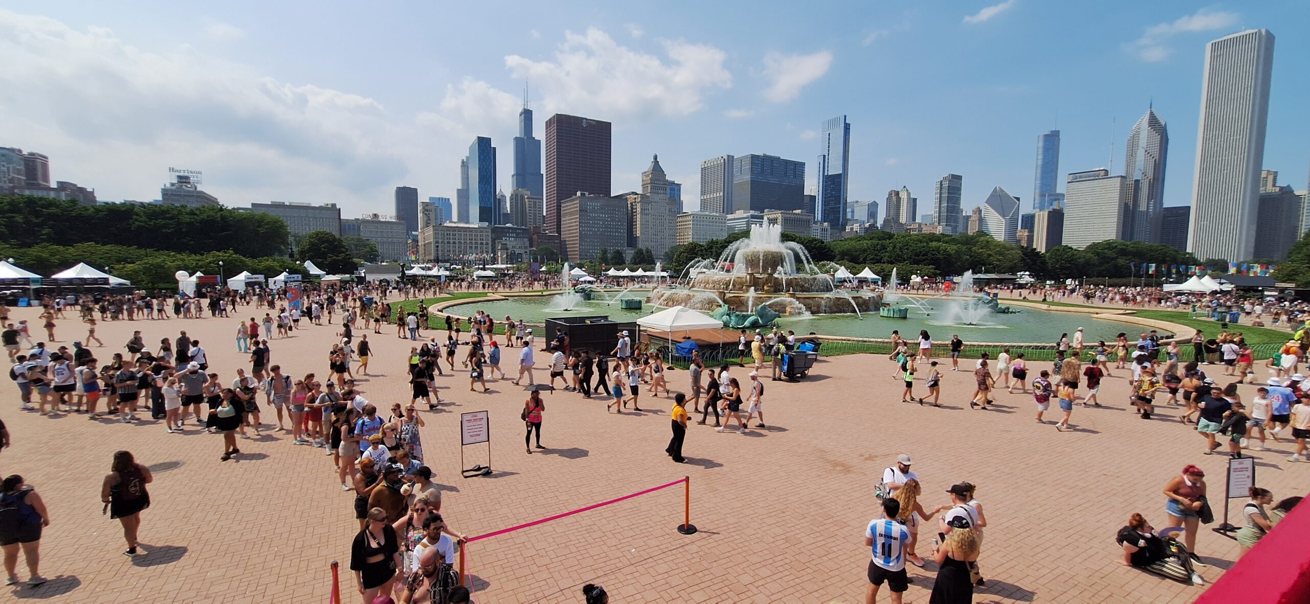 Lollapalooza Festival a crowd of people in a park with a fountain in the background