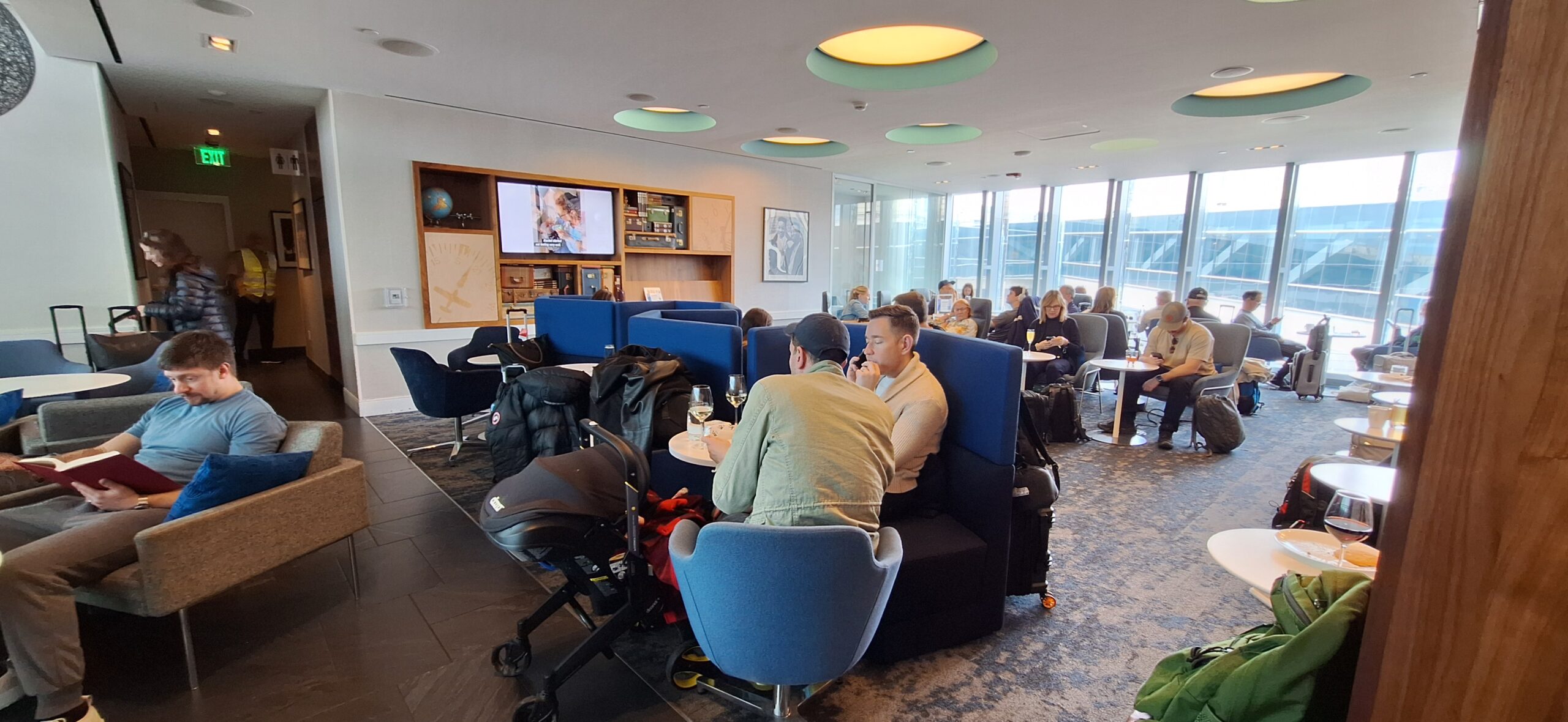 Centurion Lounge Philadelphia people sitting at tables in a room with blue chairs and blue couches
