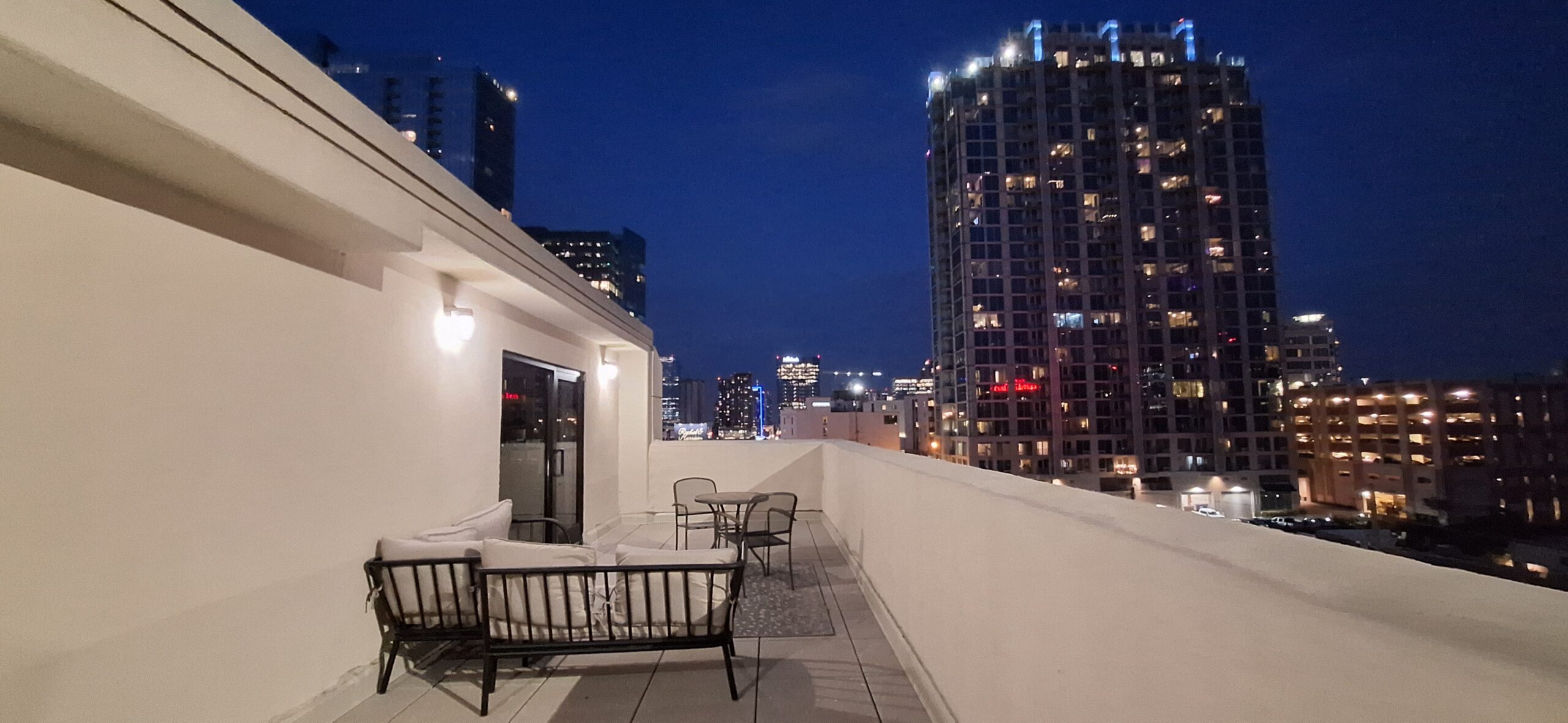 Marriott Aloft Nashville review a rooftop patio with chairs and tables and a city skyline at night
