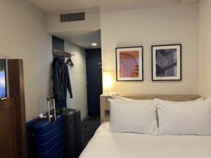Four Points Flex Osaka a bed with pillows and a suitcase in a room