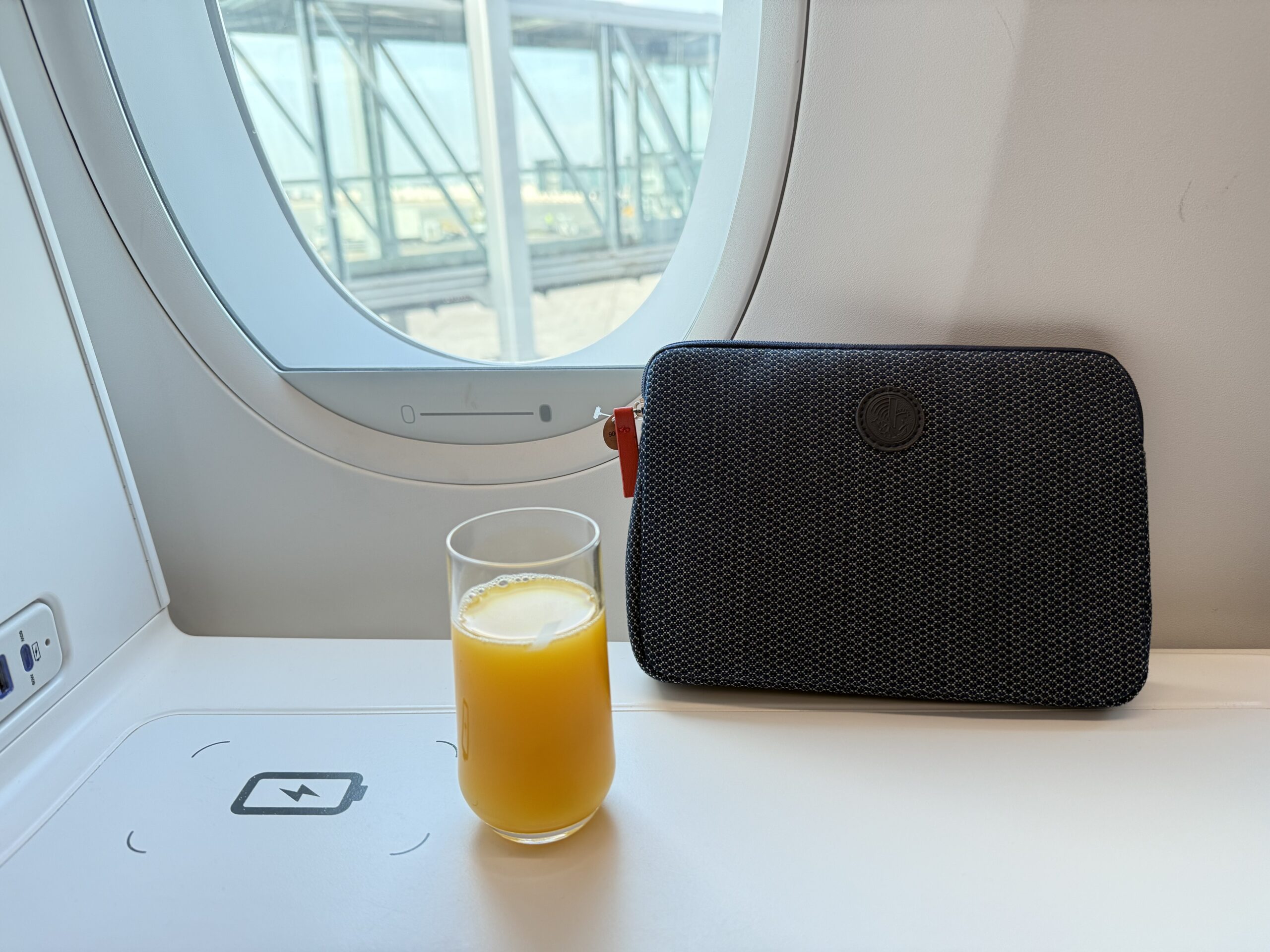 a glass of orange juice next to a purse on a table