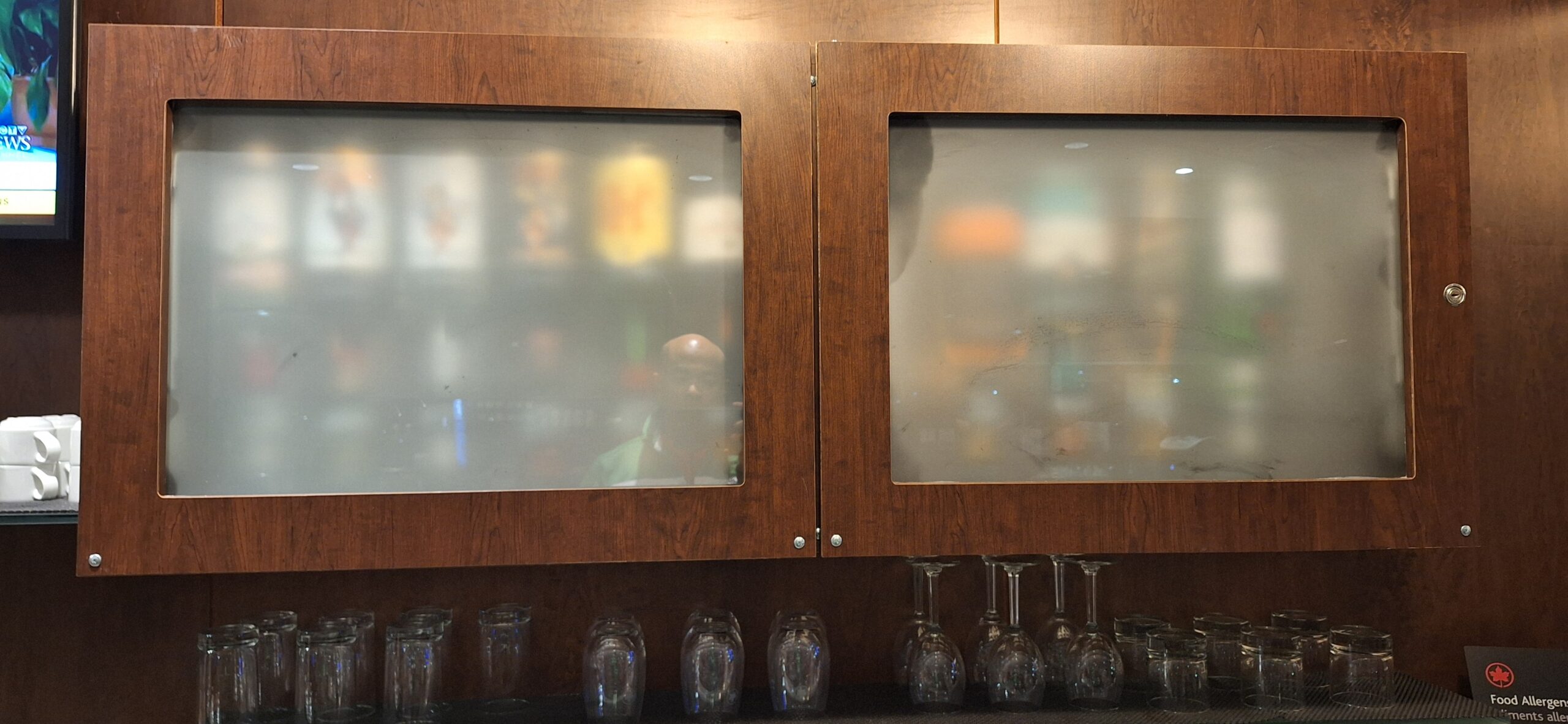 a wood cabinet with glass doors and glasses on the wall