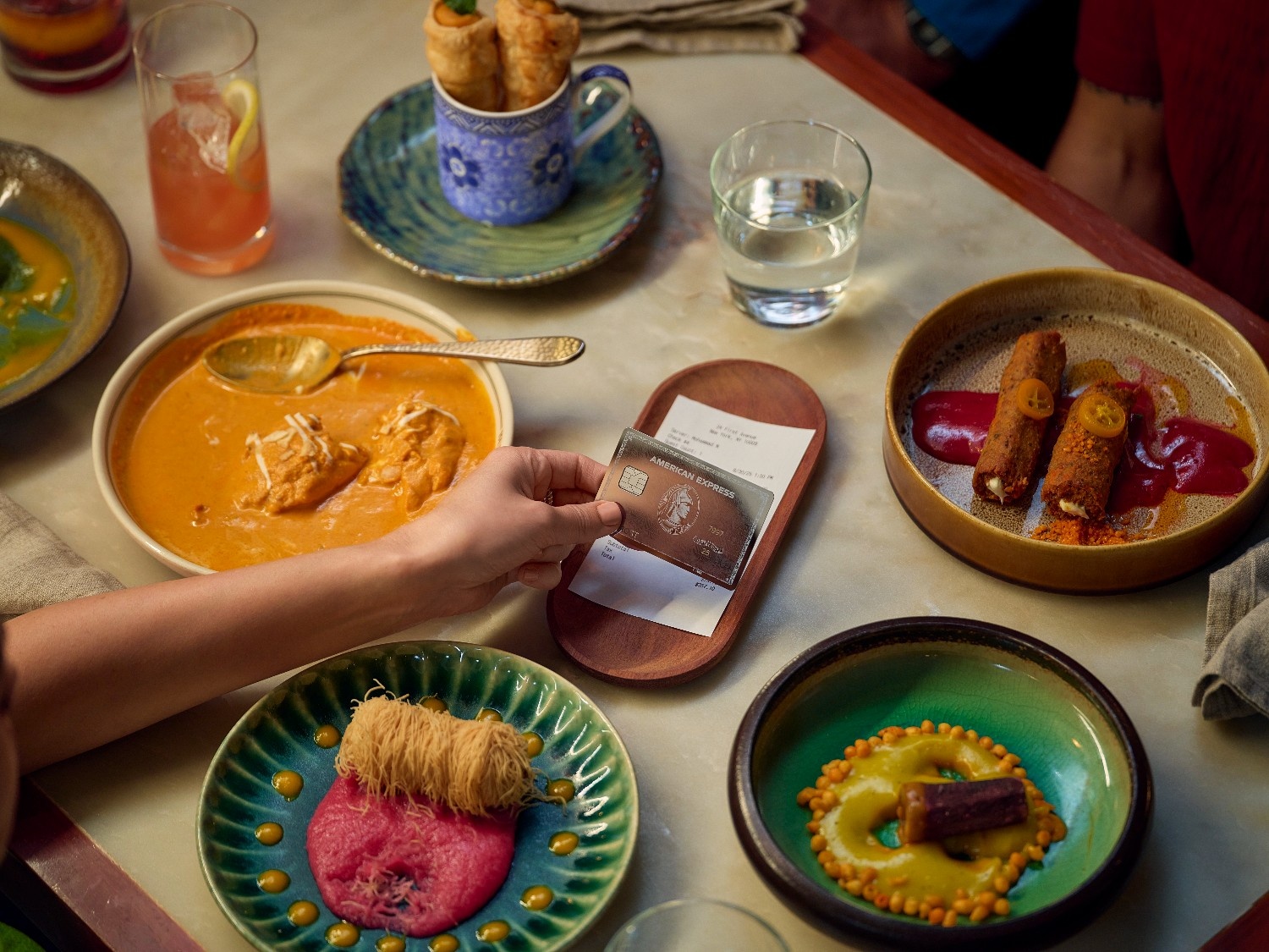 a person's hand over a table with plates of food
