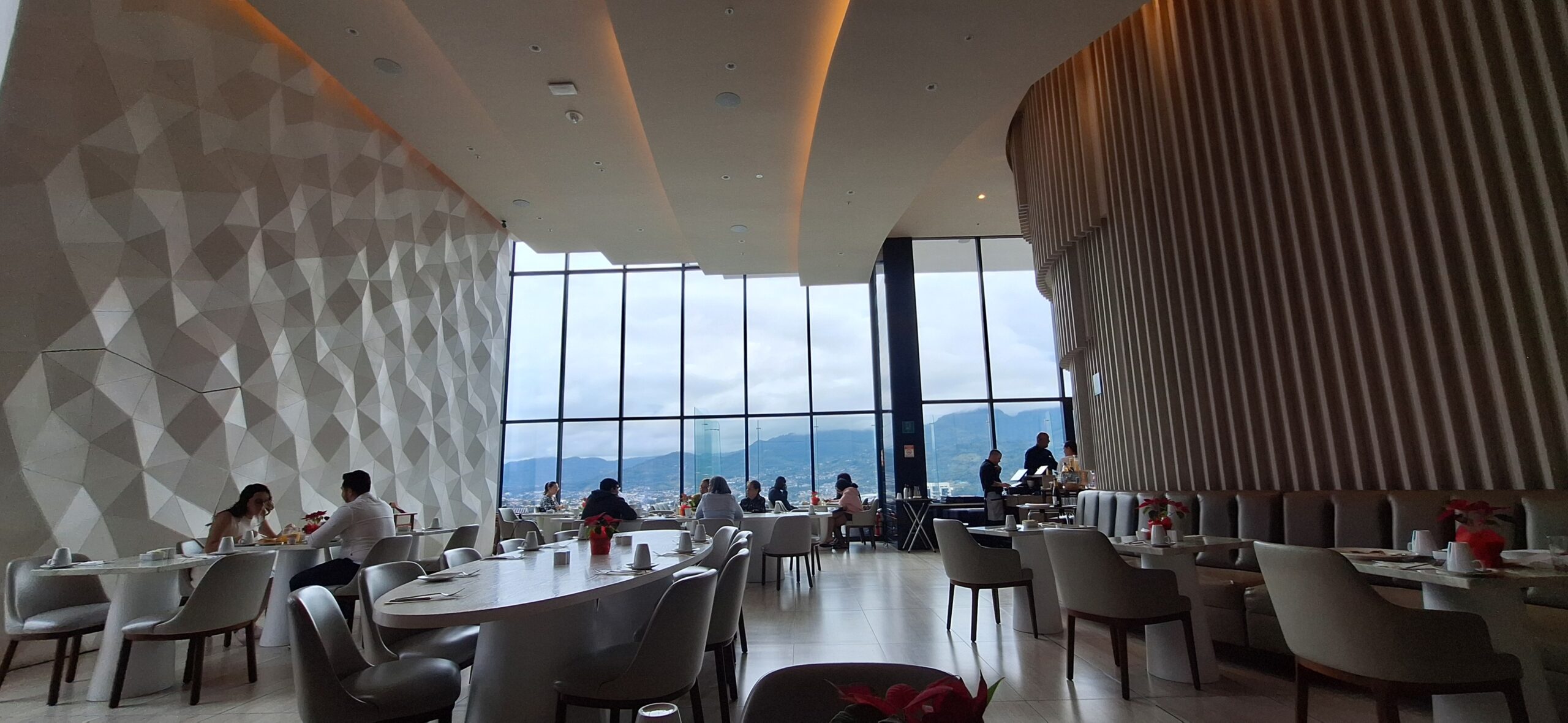 a room with many tables and chairs and a view of the city