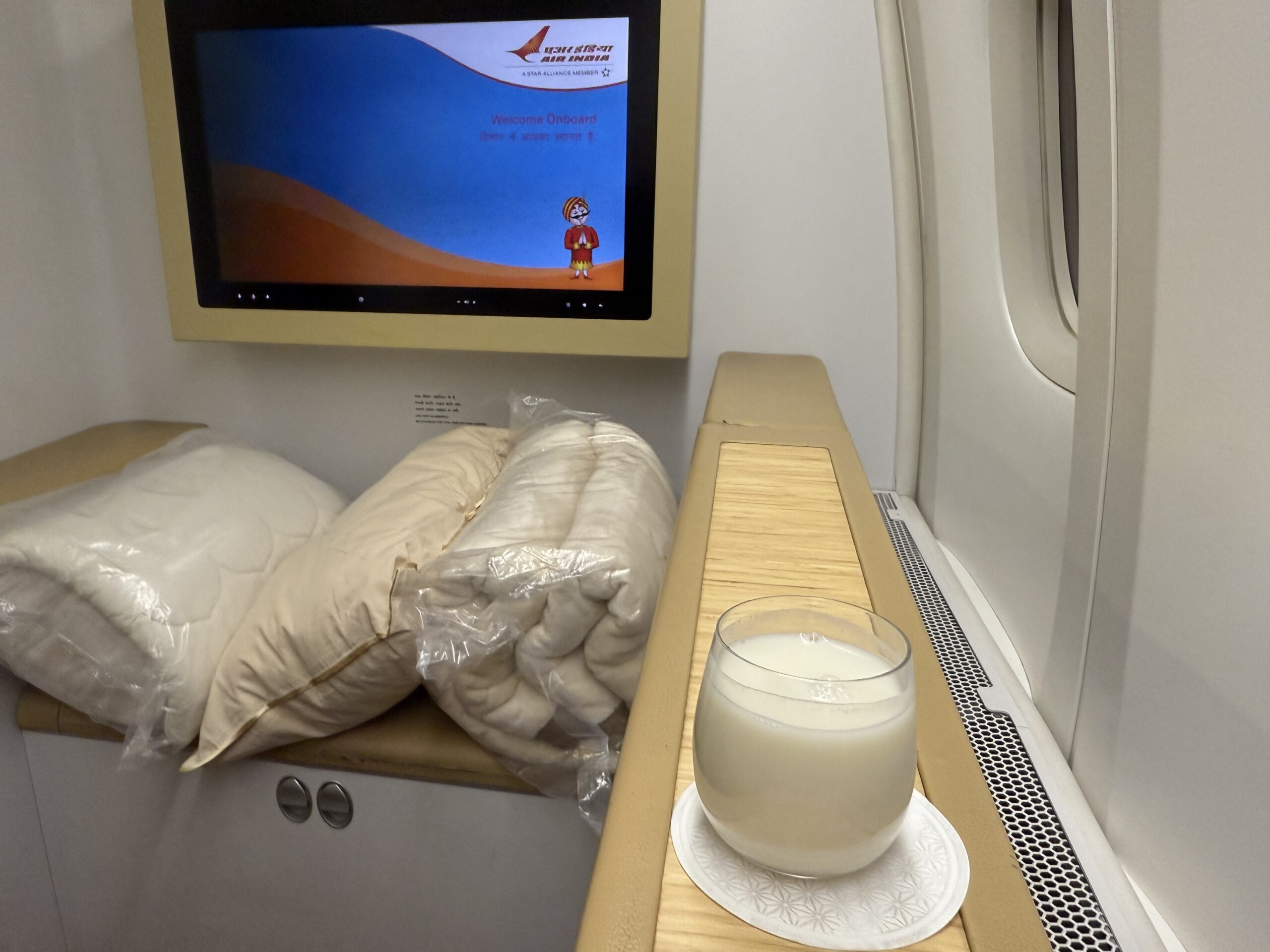 Air India First Class a glass of milk on a table with a television on the wall
