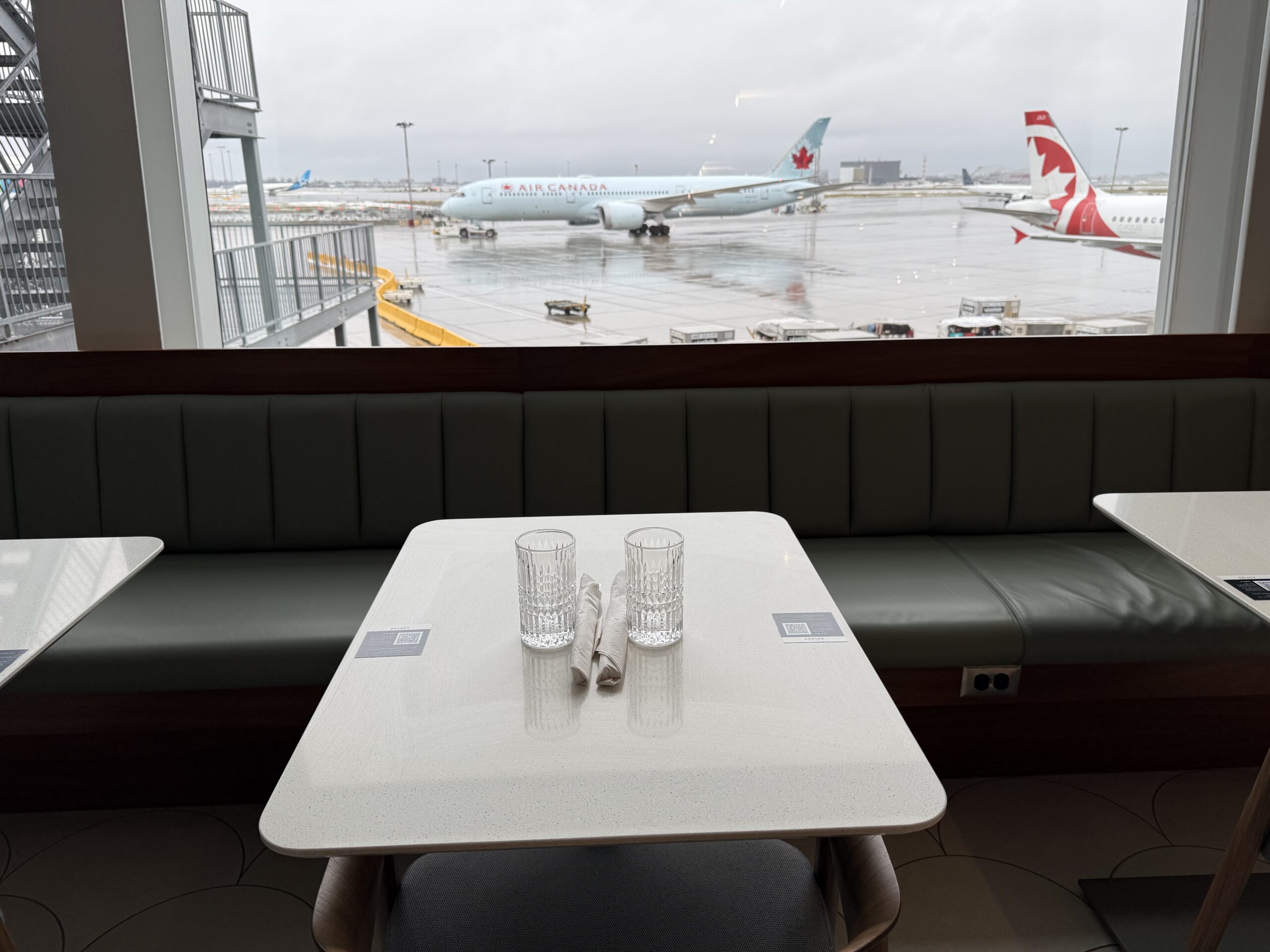 a table with glasses on it and a window with planes in the background