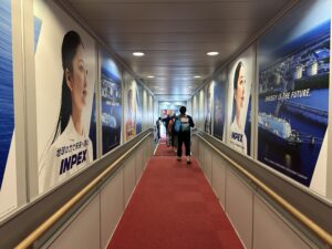 people walking down a hallway with a red carpet and a person walking