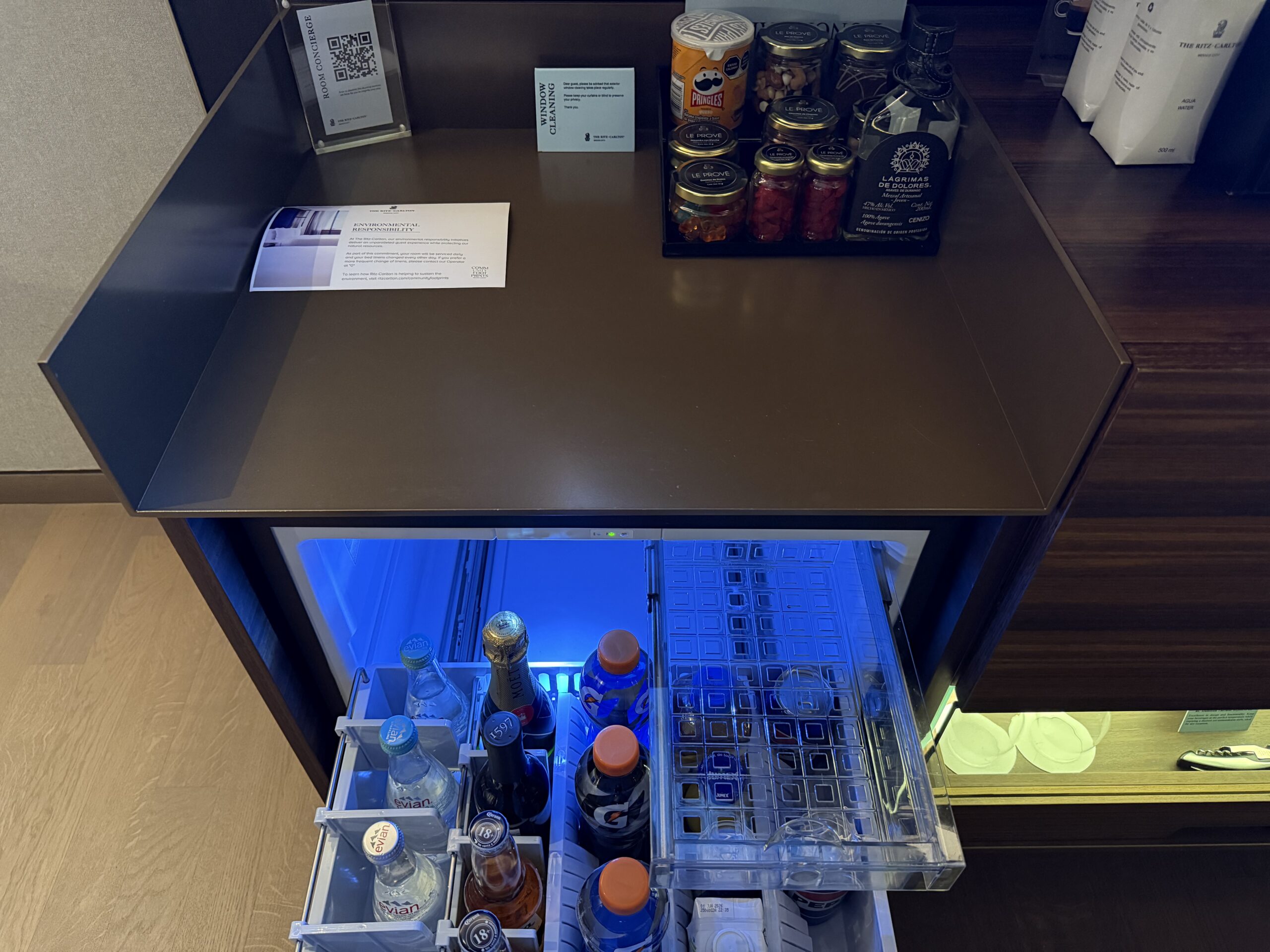a small refrigerator with a shelf full of bottles and other items