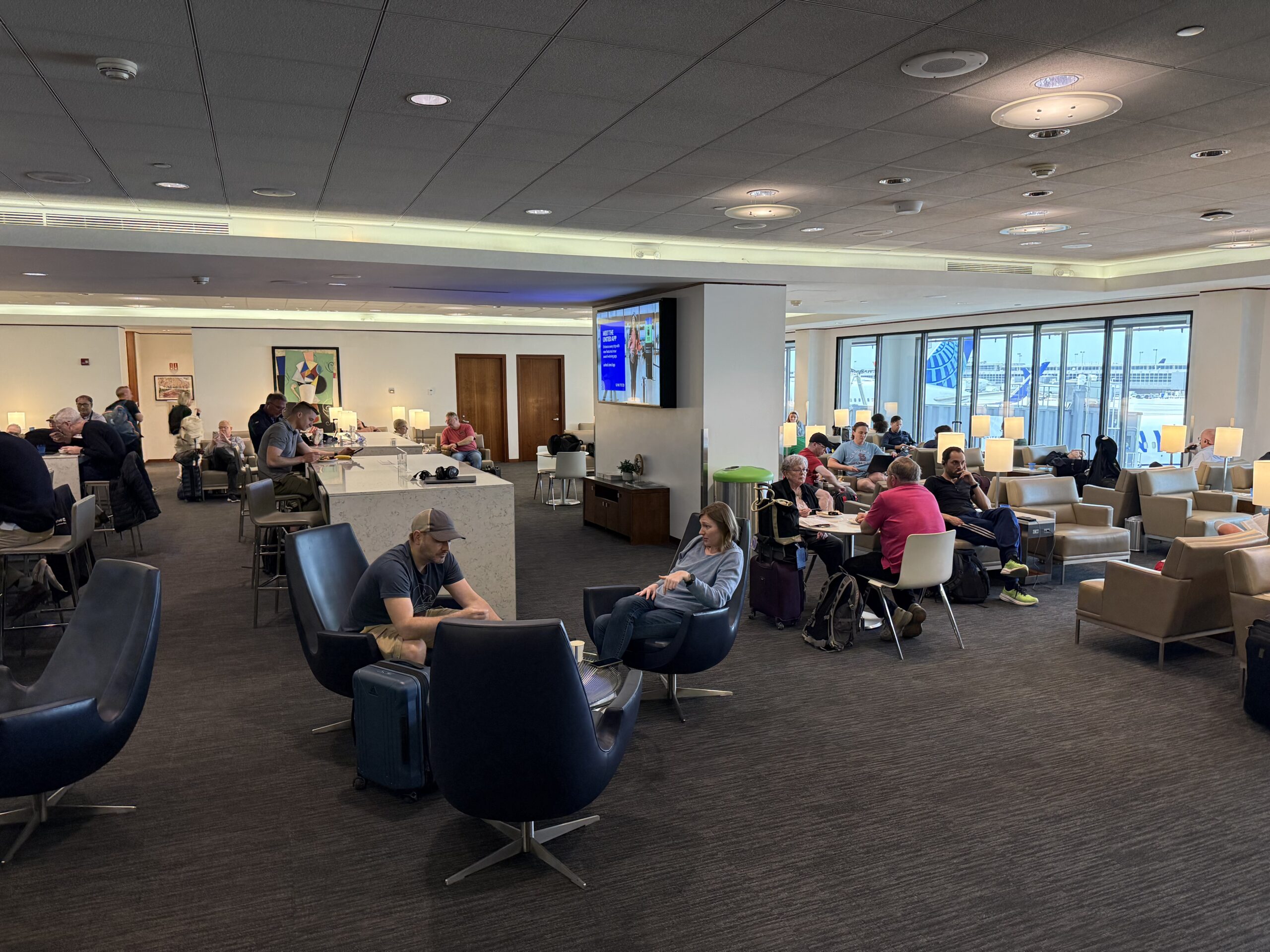 a group of people sitting in chairs in a room with a large screen