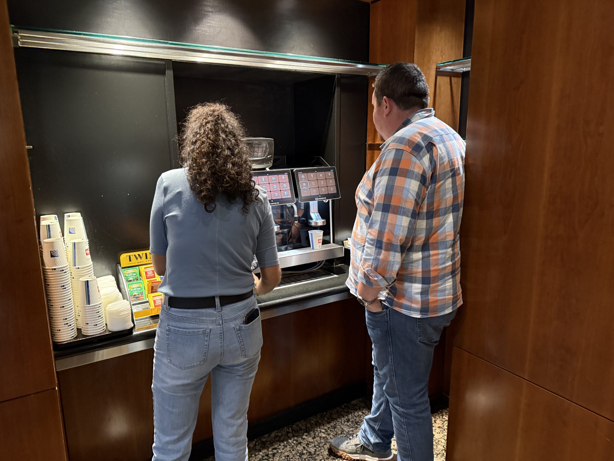a man and woman standing in front of a coffee machine