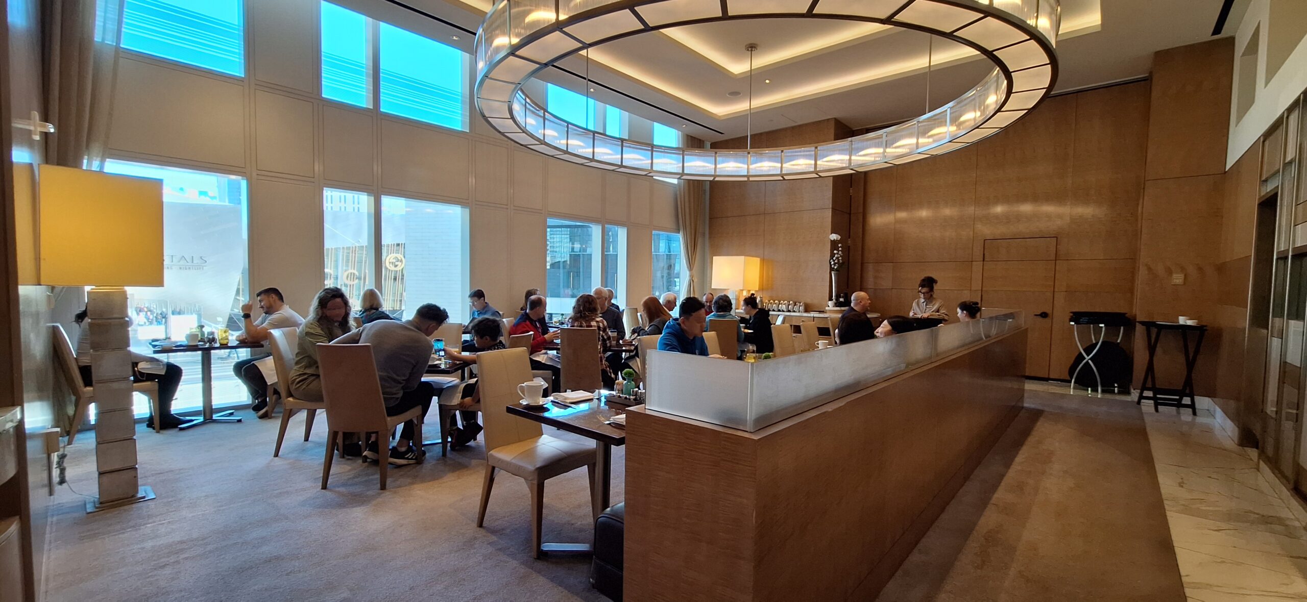 a group of people sitting at tables in a room with a chandelier