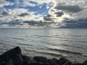 a rocky beach with water and clouds in the sky