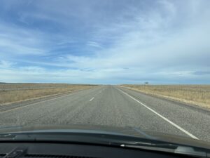 a road with grass and blue sky