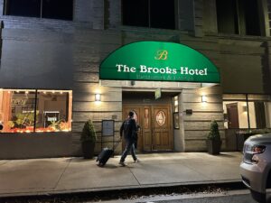 a man with luggage walking outside of a hotel
