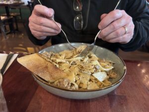 a person holding a spoon over a bowl of pasta