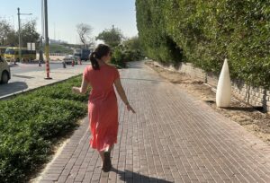a woman in a pink dress walking on a brick path
