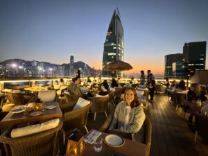 a woman sitting at a table with a city in the background