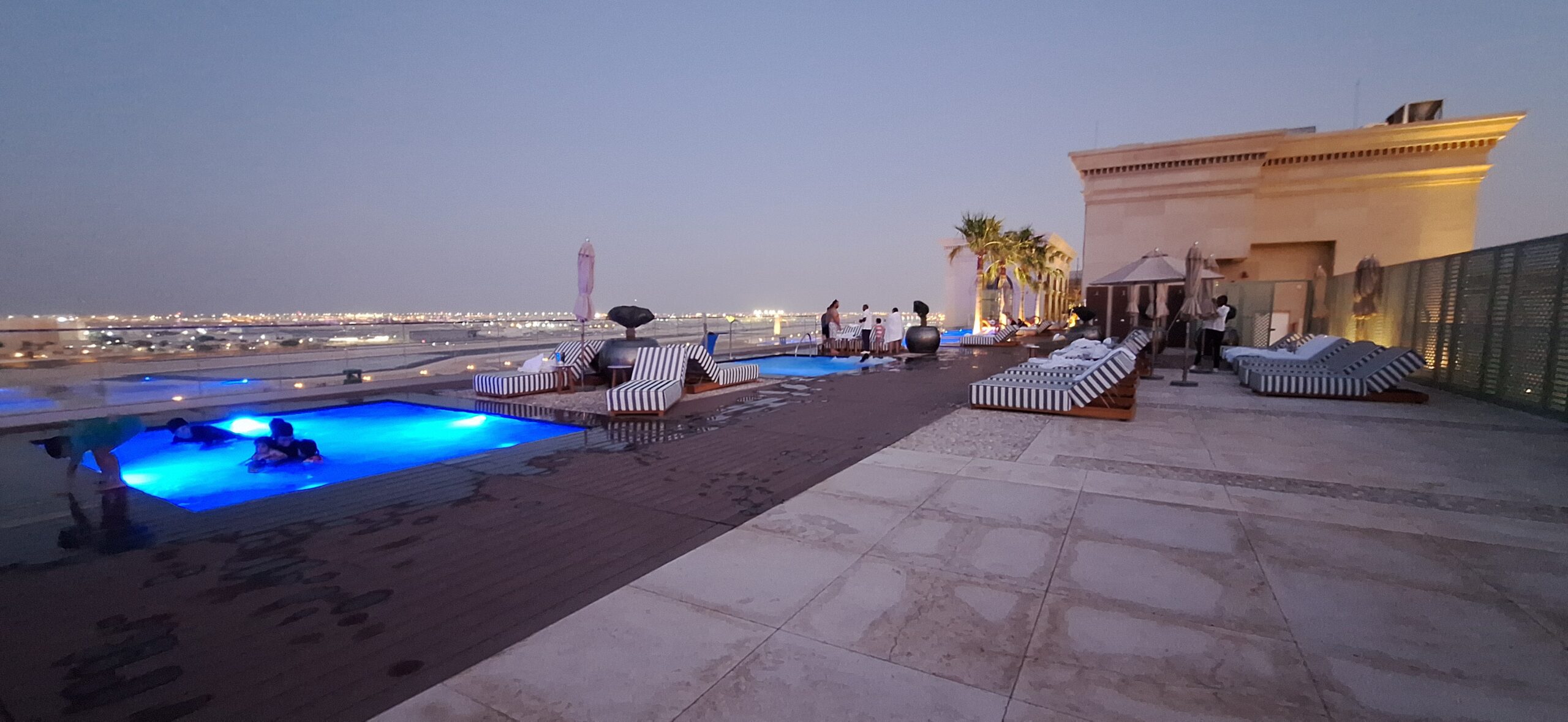 a pool with lounge chairs and a building with a body of water