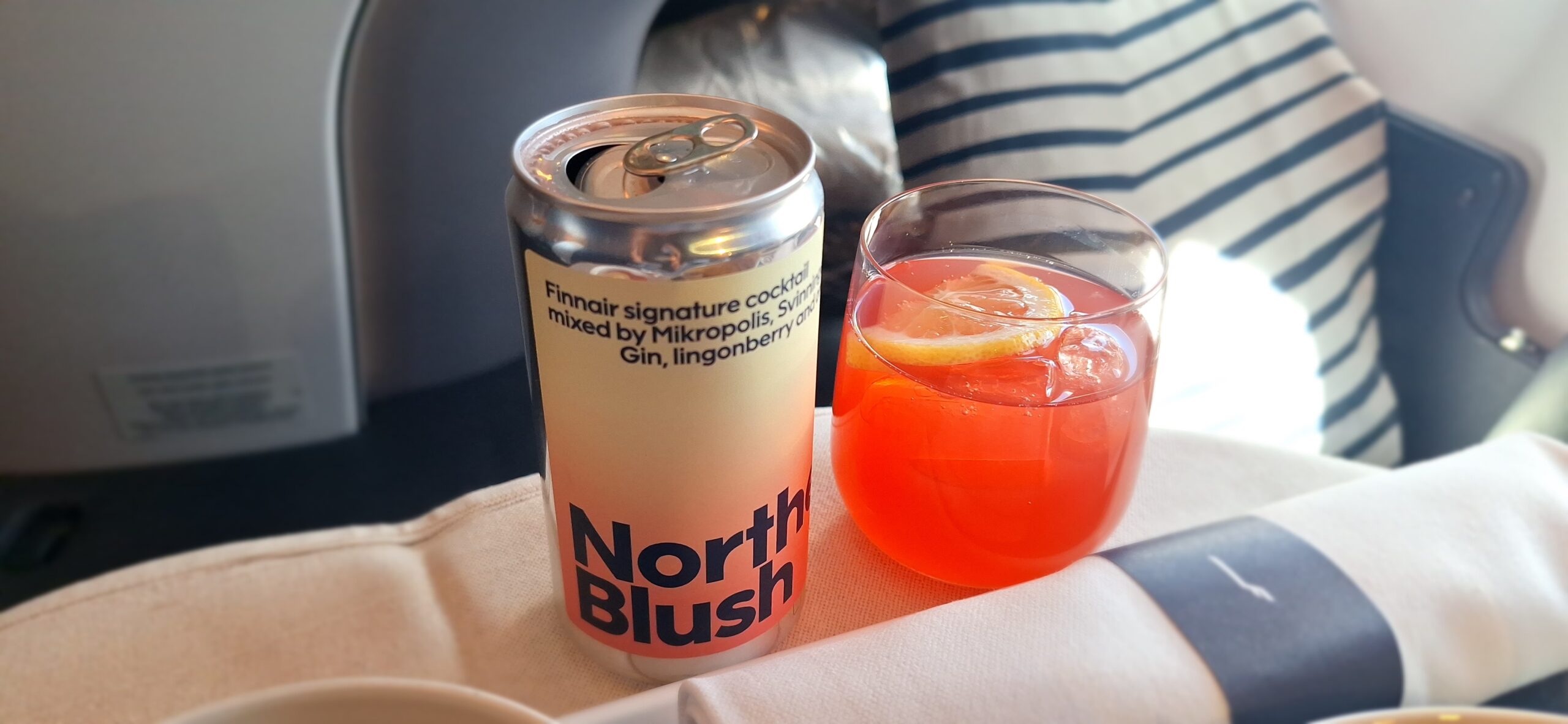 a can of drink next to a glass of liquid