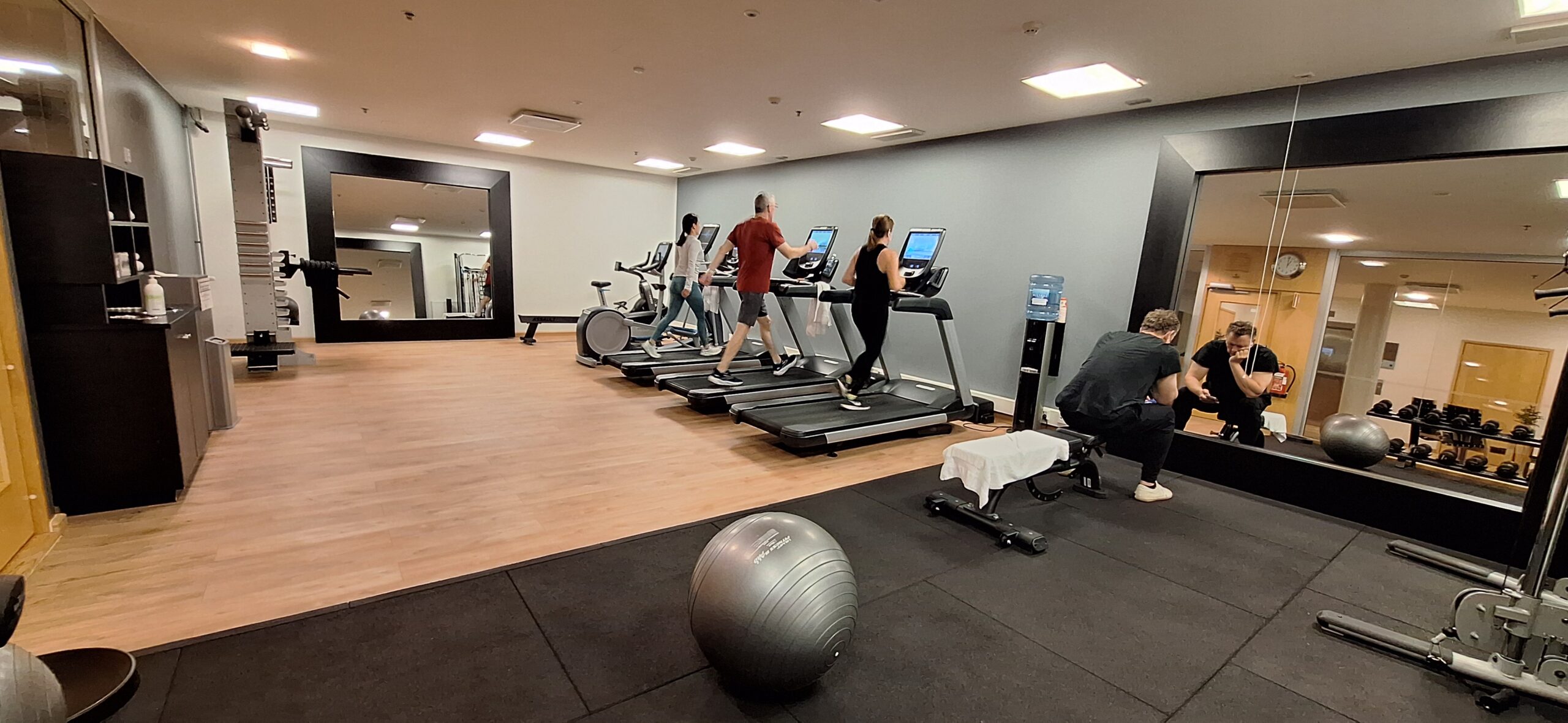 people in a gym with a group of people on treadmills