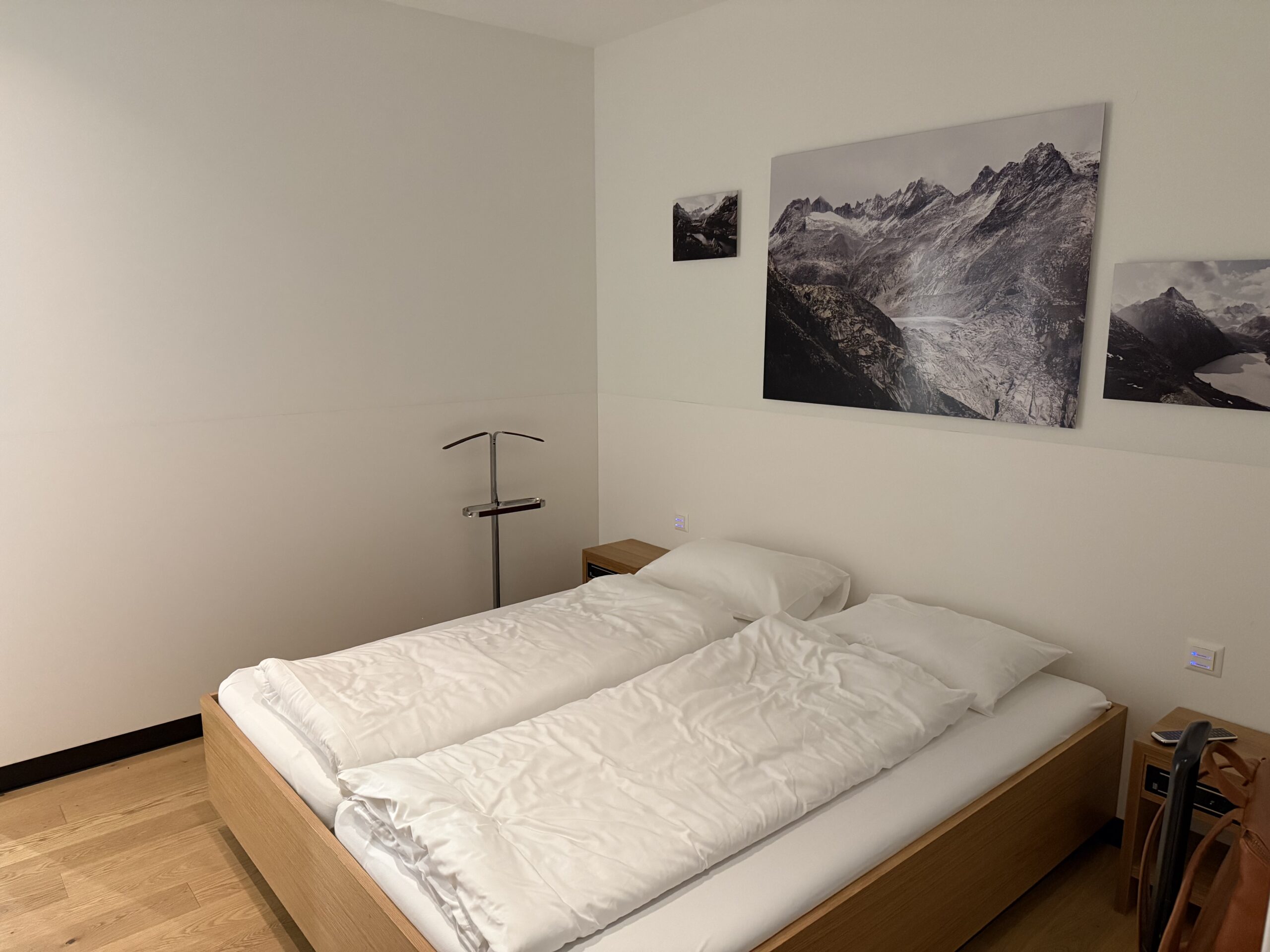 a bed with white sheets and pillows in a room with a picture on the wall